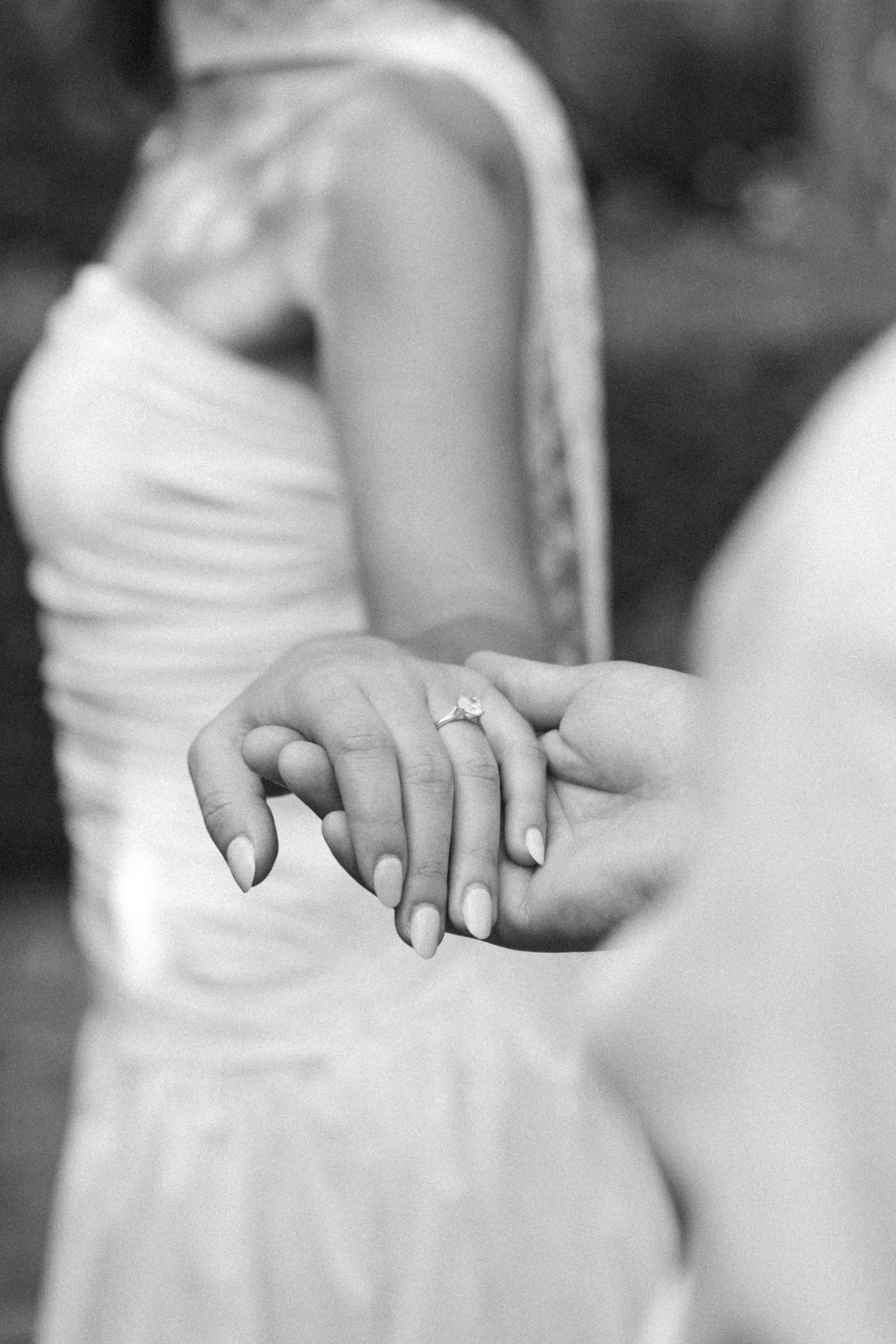 Black and white photo of bride showing off engagement ring while holding hands with partner at the Kingwood Garden Center in Columbus, Ohio