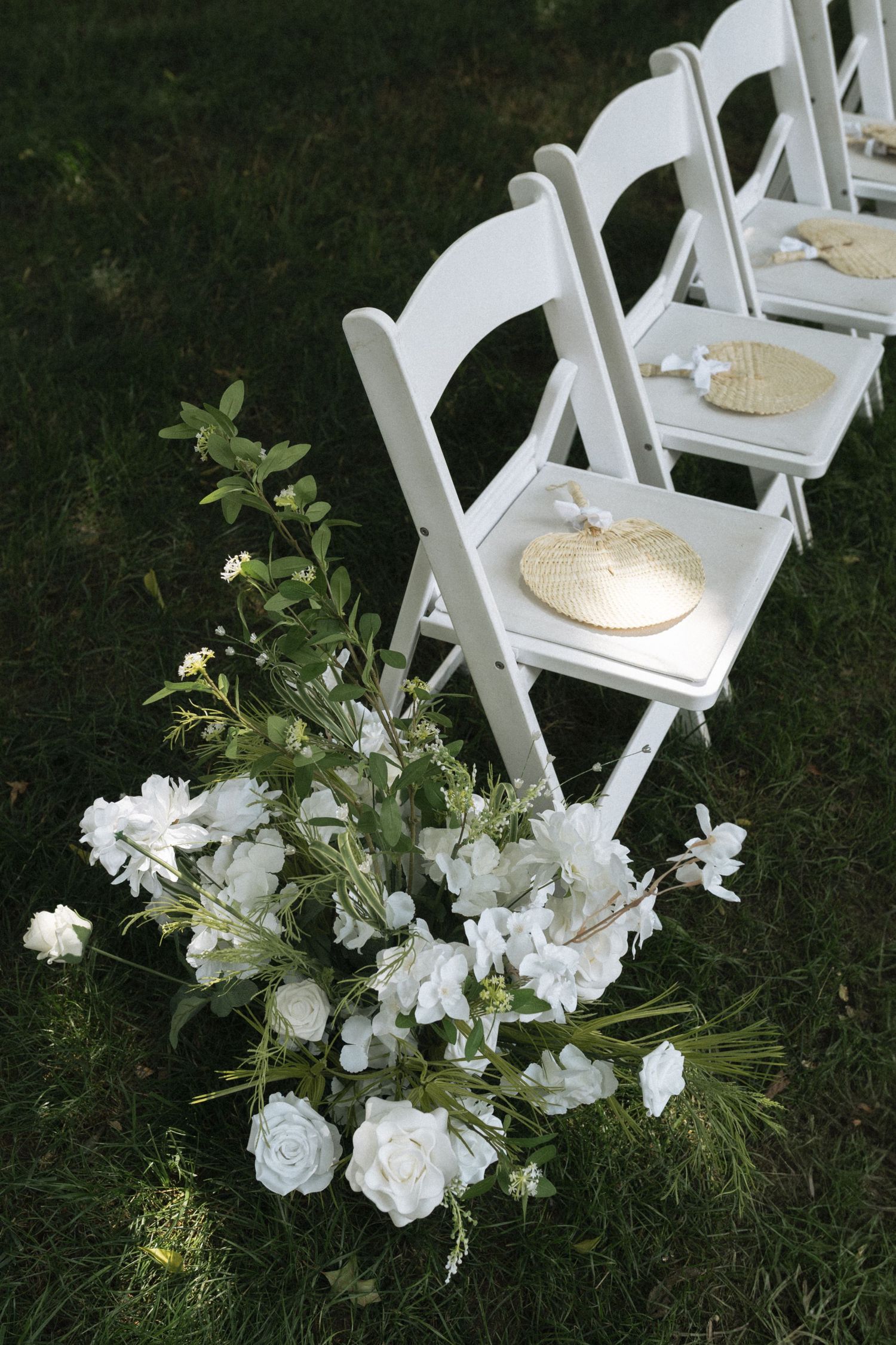 White folding chairs arranged in rows on grass with delicate white floral decorations creating an elegant outdoor wedding setup in Nashville