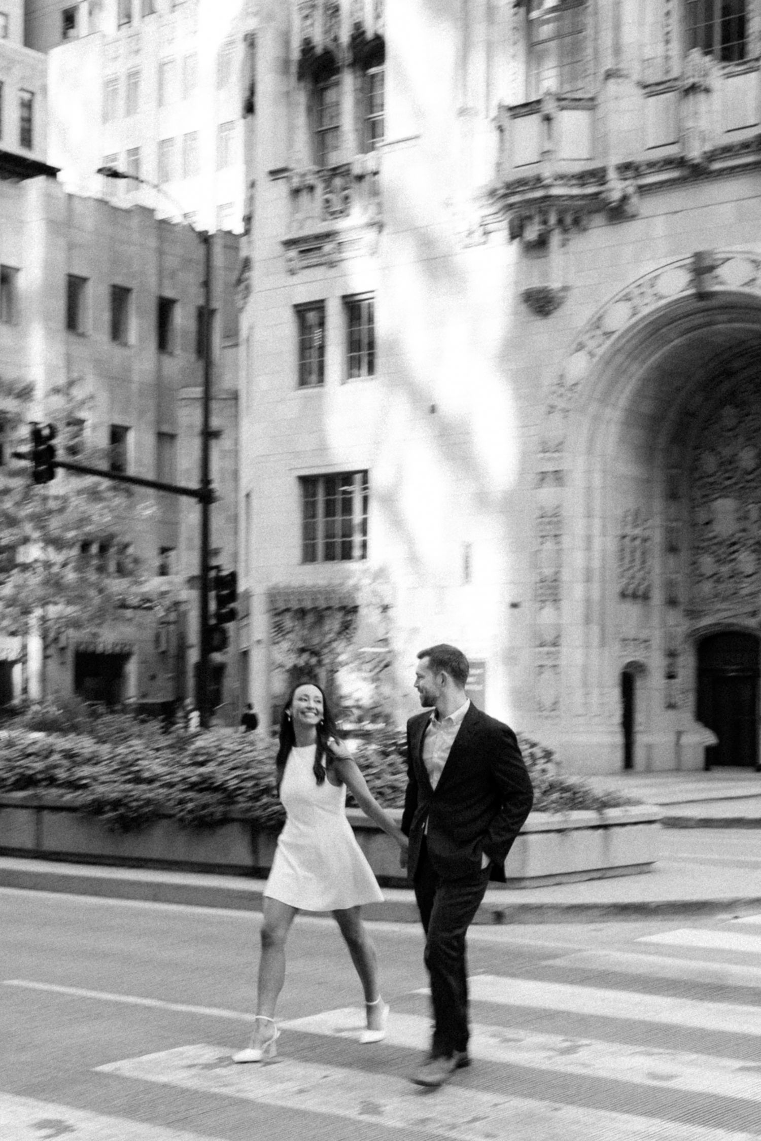 A black and white photo showing a couple holding hands and quickly walking across a crosswalk in Downtown Chicago
