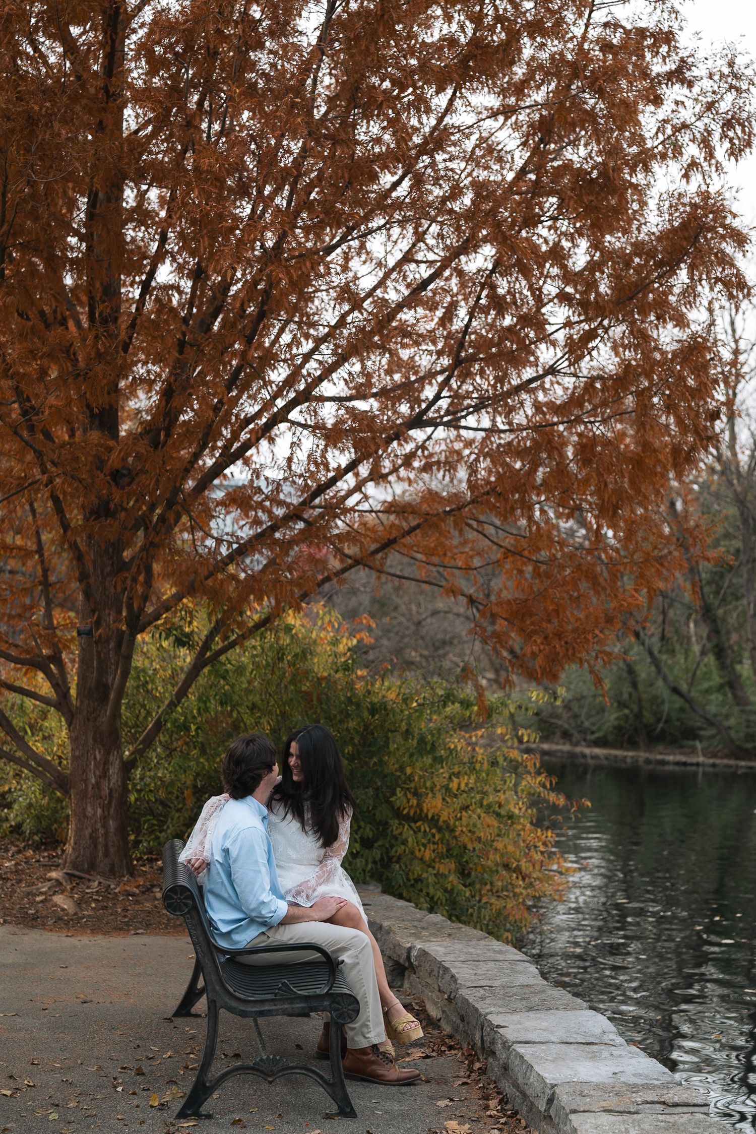 A couple sitting together on a park bench in Centennial Park surrounded by autumn trees with orange foliage