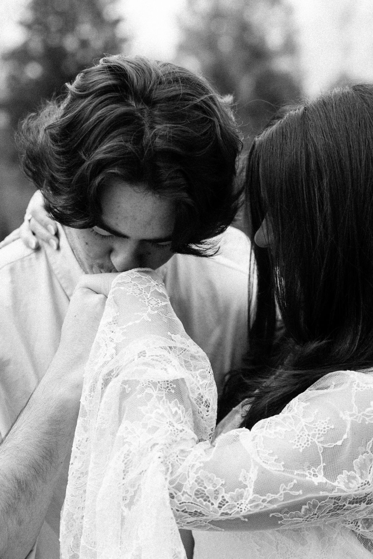 A romantic black and white photo shows a couple in close embrace wearing formal wedding attire with delicate lace details.