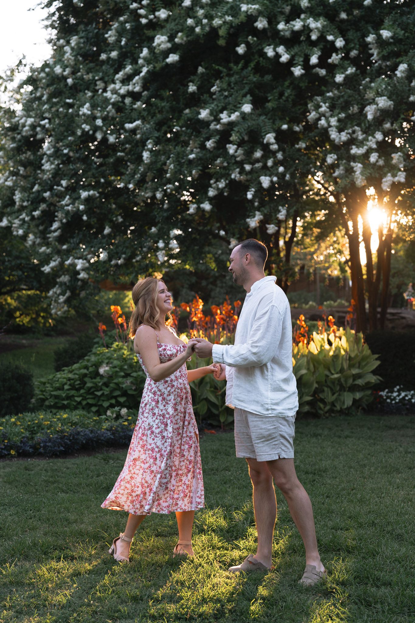 A couple shares a heartwarming moment together in a garden at sunset with golden sunlight filtering through trees in Nashville