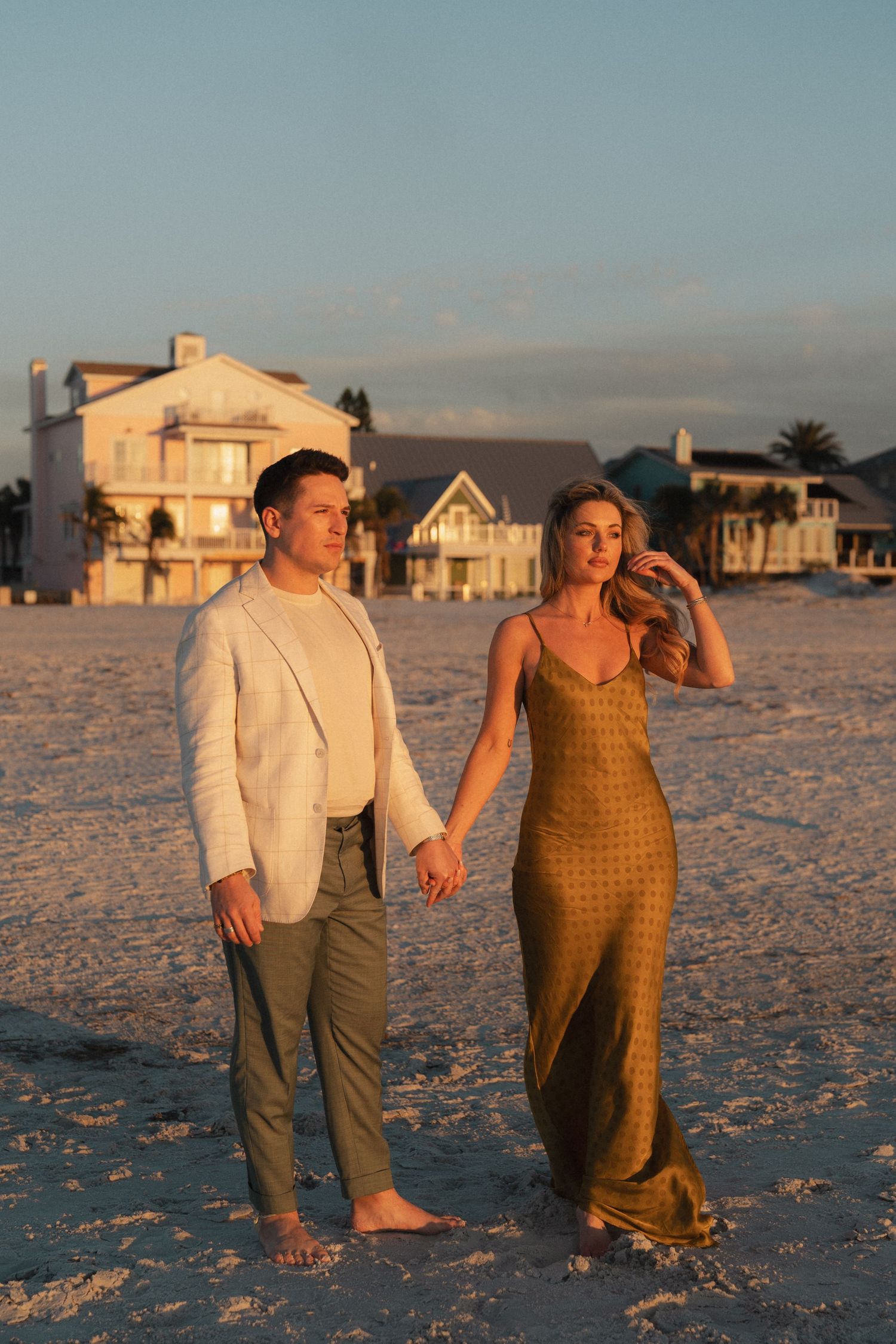 A couple walks together on a sandy beach during sunset in golden hour lighting at Clearwater Beach, Florida