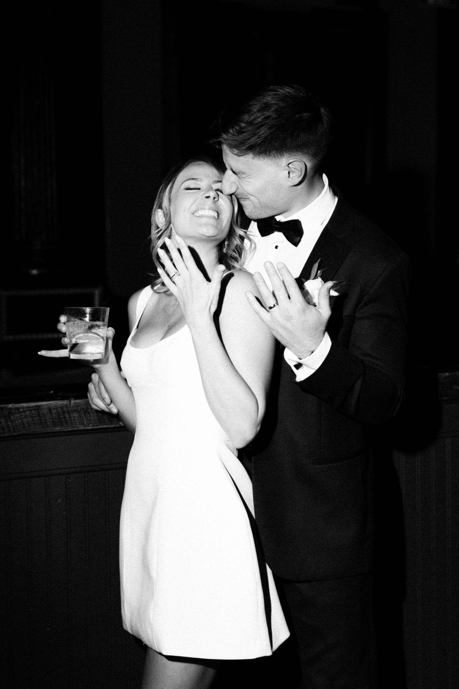 A couple shares an intimate moment at a formal event, with the woman in white and man in tuxedo dancing together.