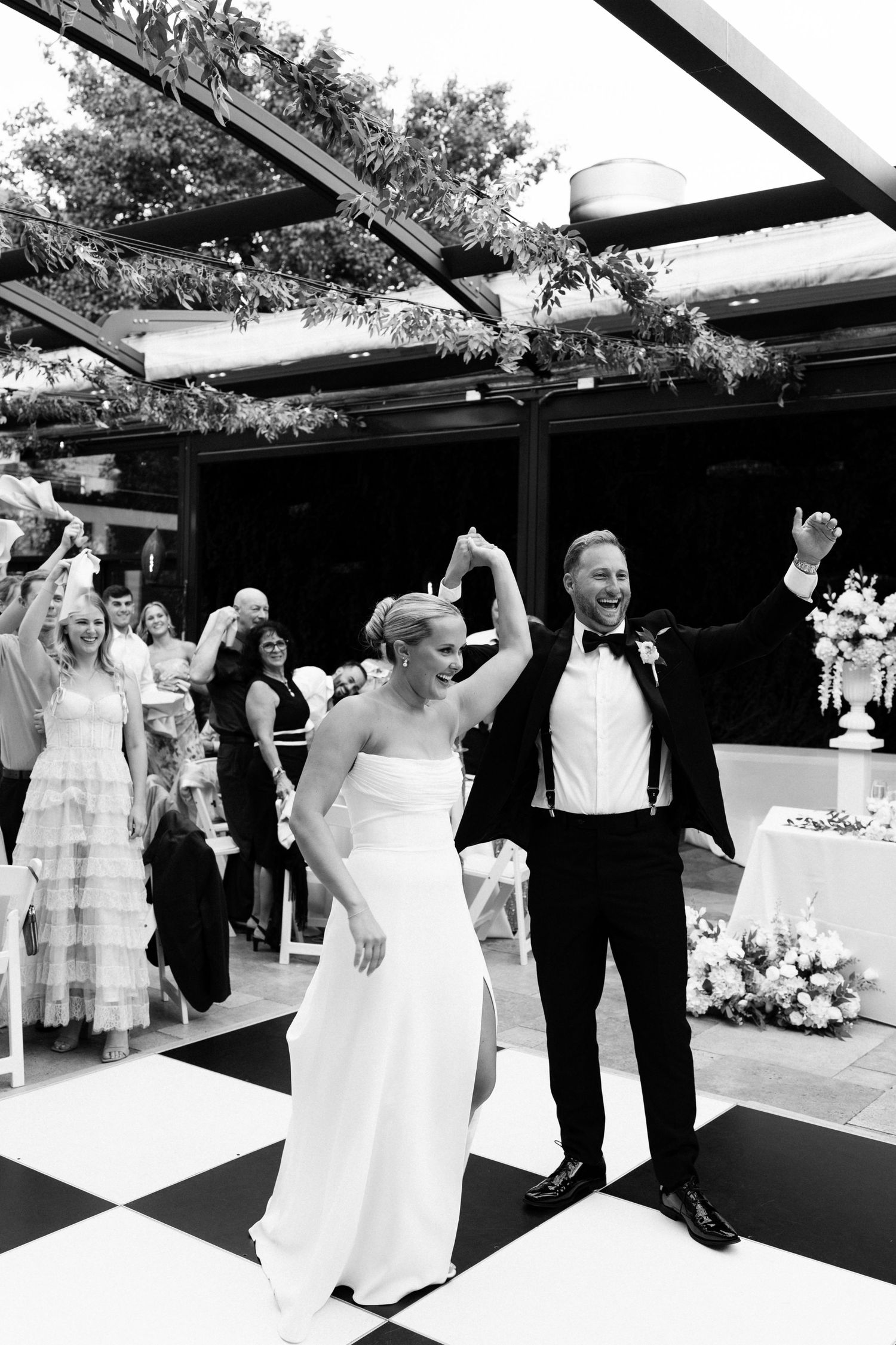 Bride and groom enter onto the black and white checkered dance floor at outdoor reception celebration in Chicago