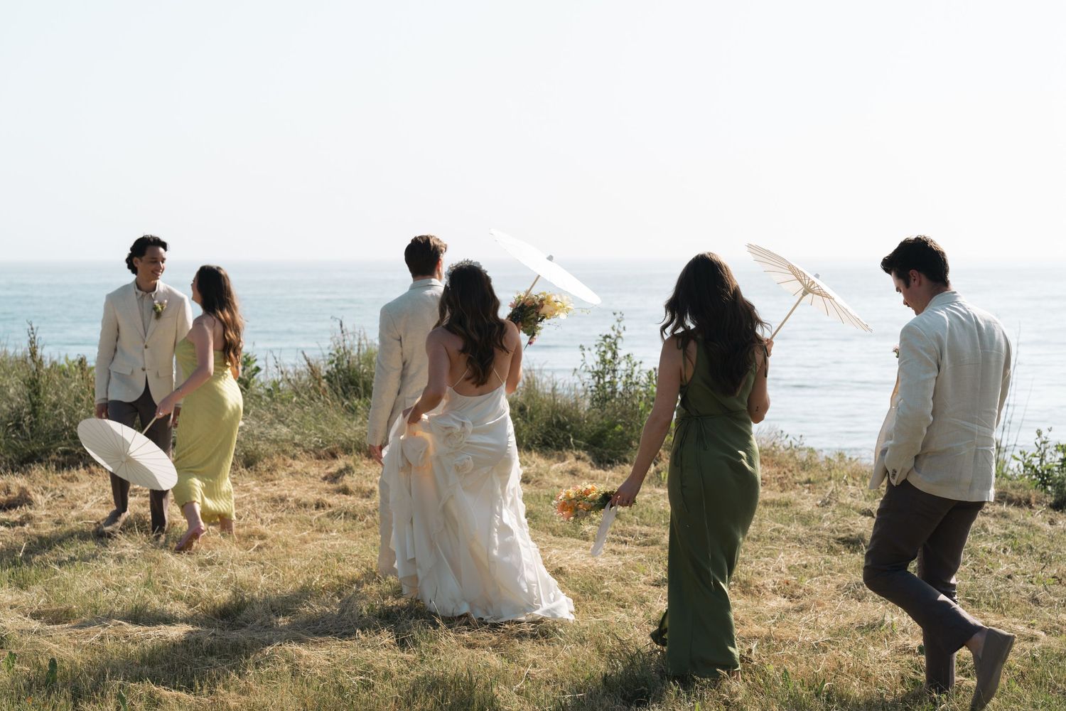 A group of people run joyfully up a grassy hillside together in a playful sequence in California