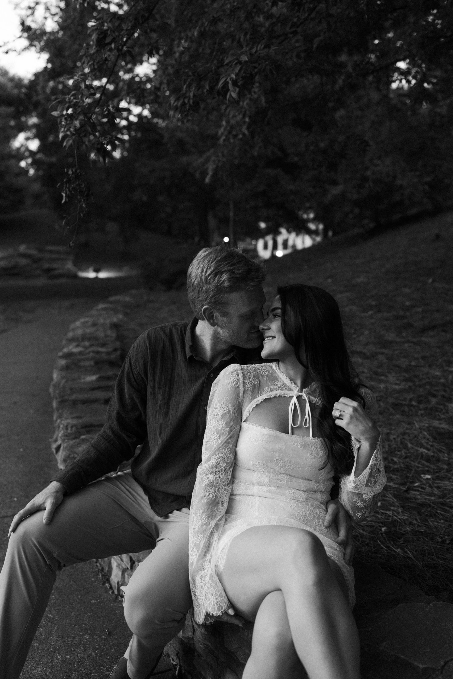 A romantic black and white photo shows a couple embracing in a park setting in Nashville