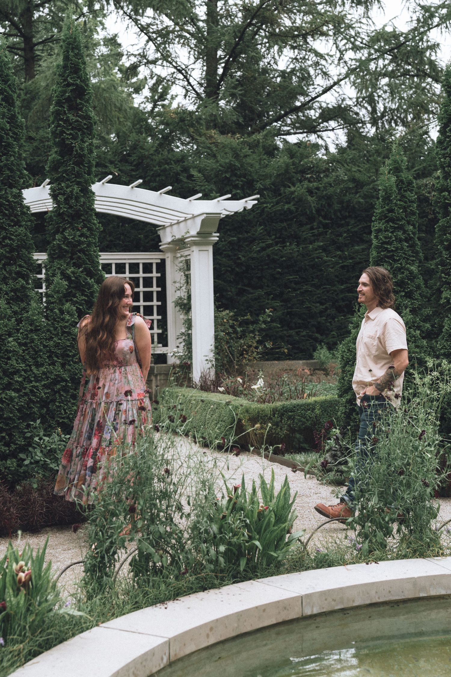 Romantic couples enjoy a garden along a curved white wall with greenery in Indianapolis