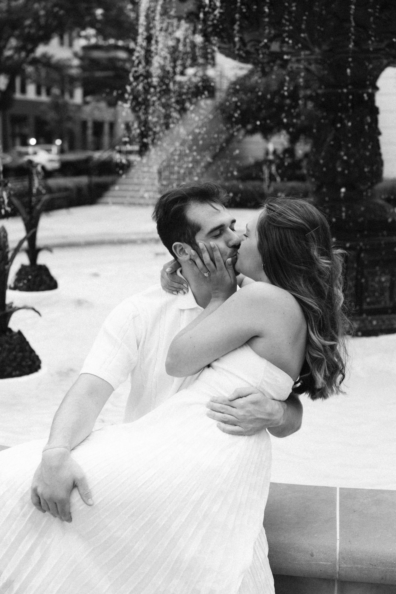 A romantic couple shares a tender kiss while being photographed in a black and white photo in Carmel, Indiana