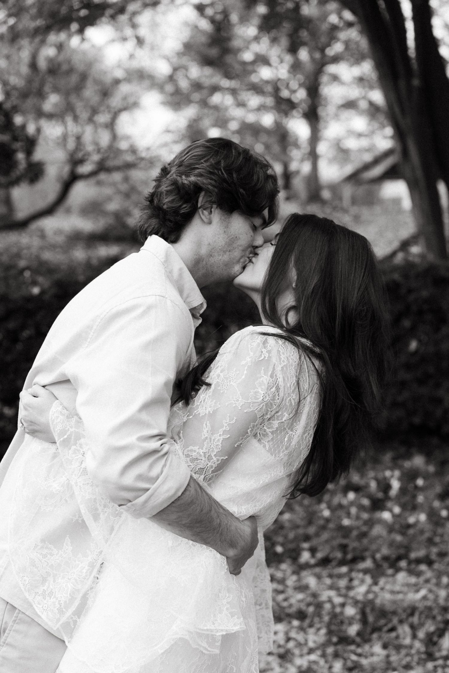 A romantic couple in white outfits sharing tender kisses with each other in a peaceful outdoor setting in Nashville