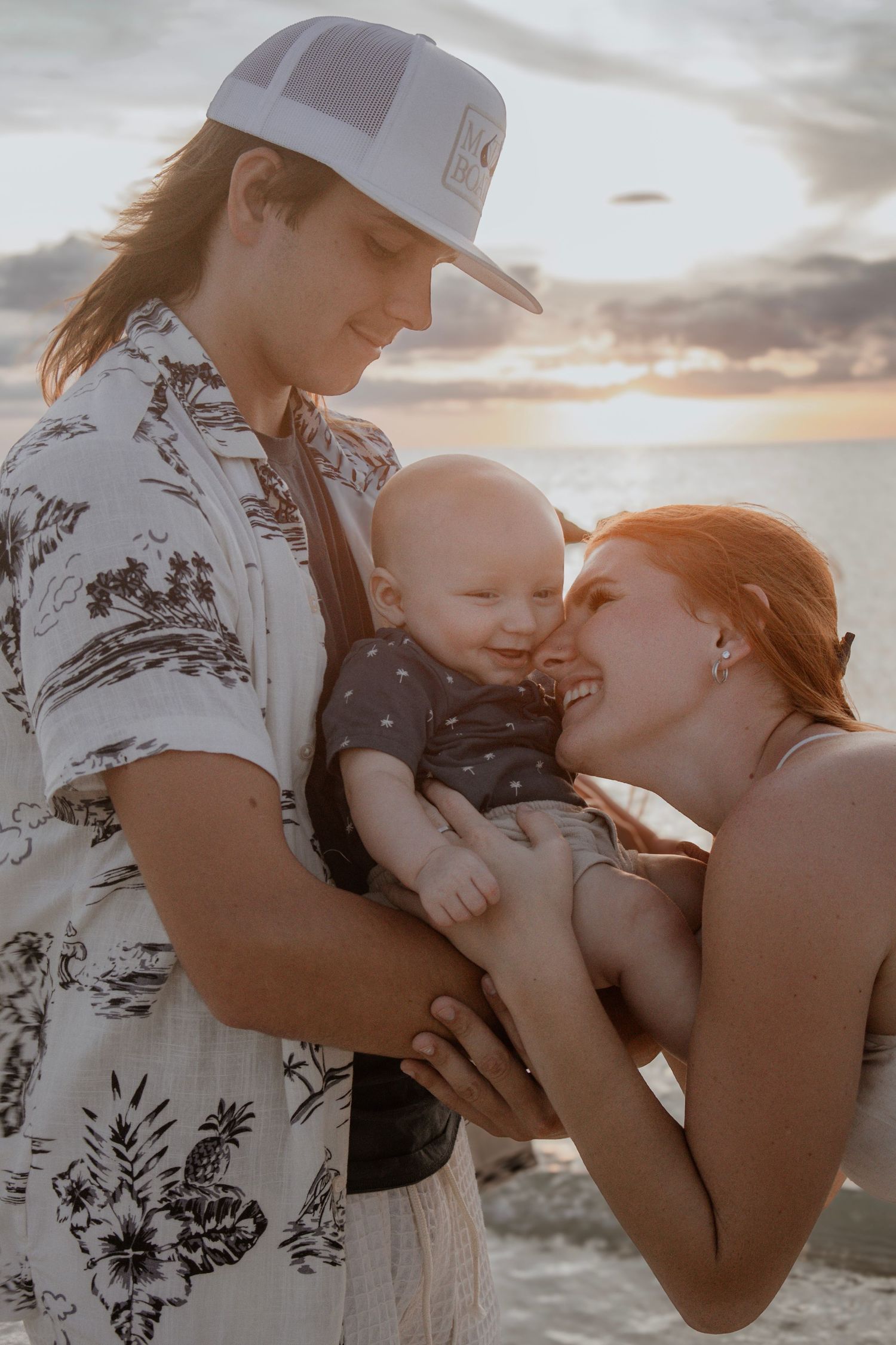 A touching family moment captured at sunset on the beach with a baby.