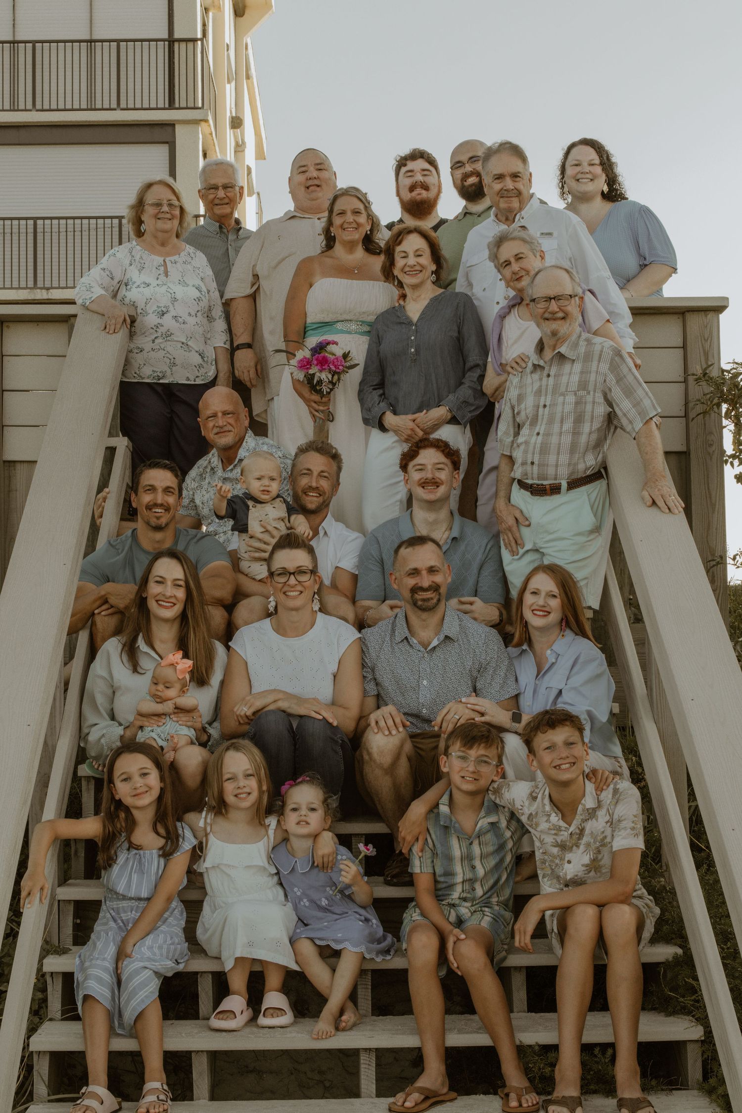 Large family group posed together on wooden deck stairs.
