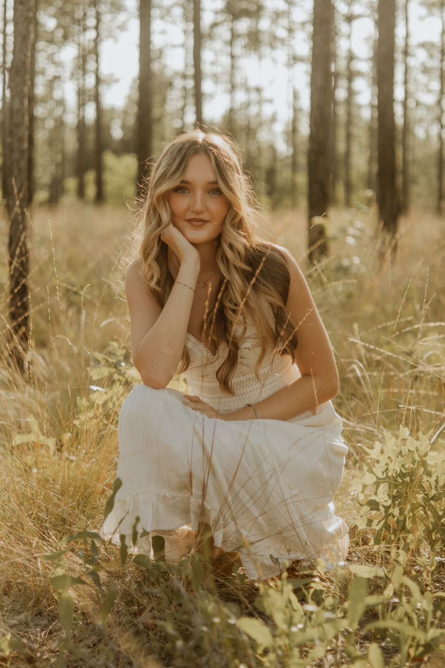 A dreamy portrait in a sunlit forest meadow with a white dress and tall grass creating a romantic atmosphere.