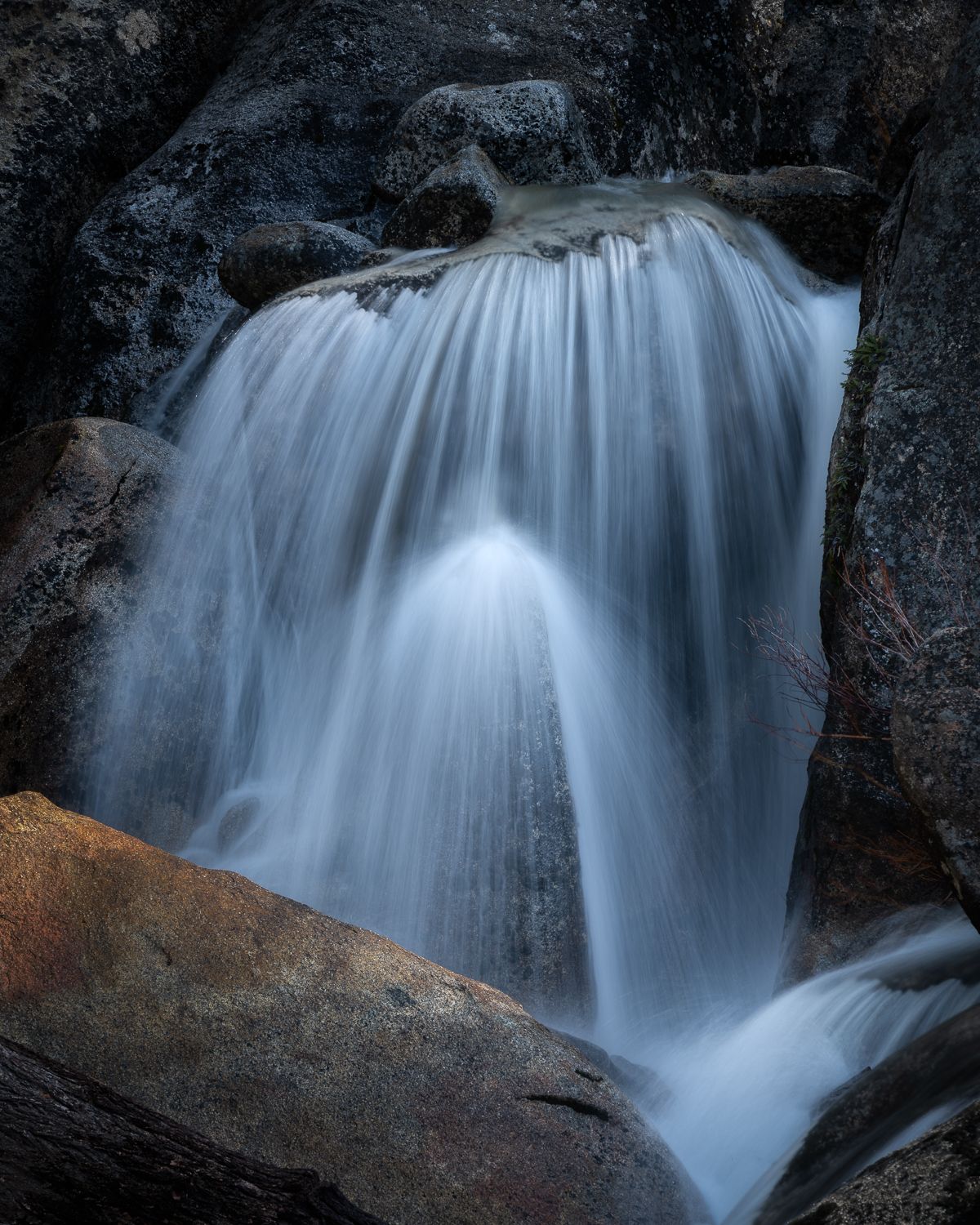 Silky waterfall cascading over dark rocks with smooth water motion effect.