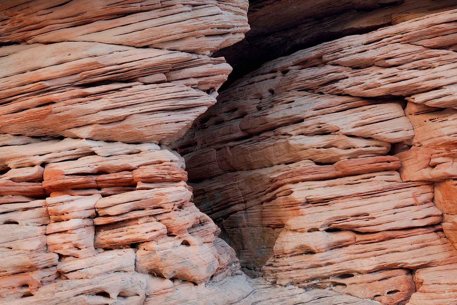 Layered sandstone rock formations create dramatic patterns and textures in red desert cliffs.
