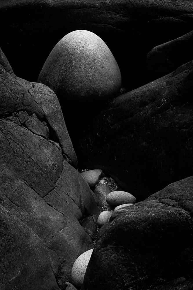 Black granite boulders create dramatic shadows and textures in an artistic rock formation composition.