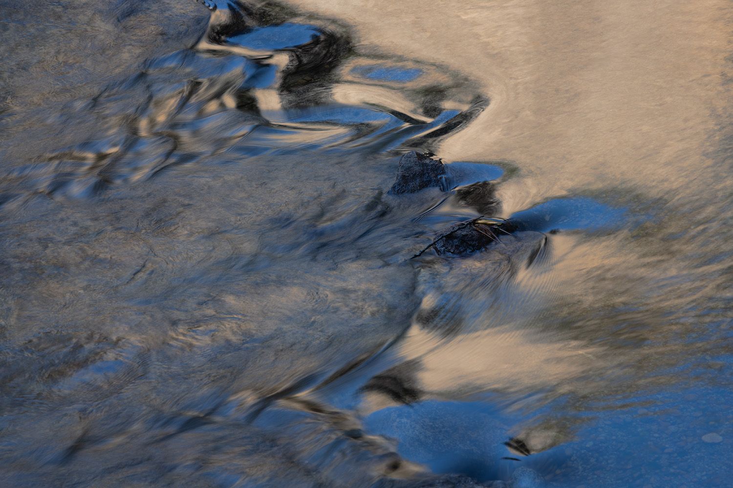 Abstract water reflections create rippling patterns in blue and golden tones.