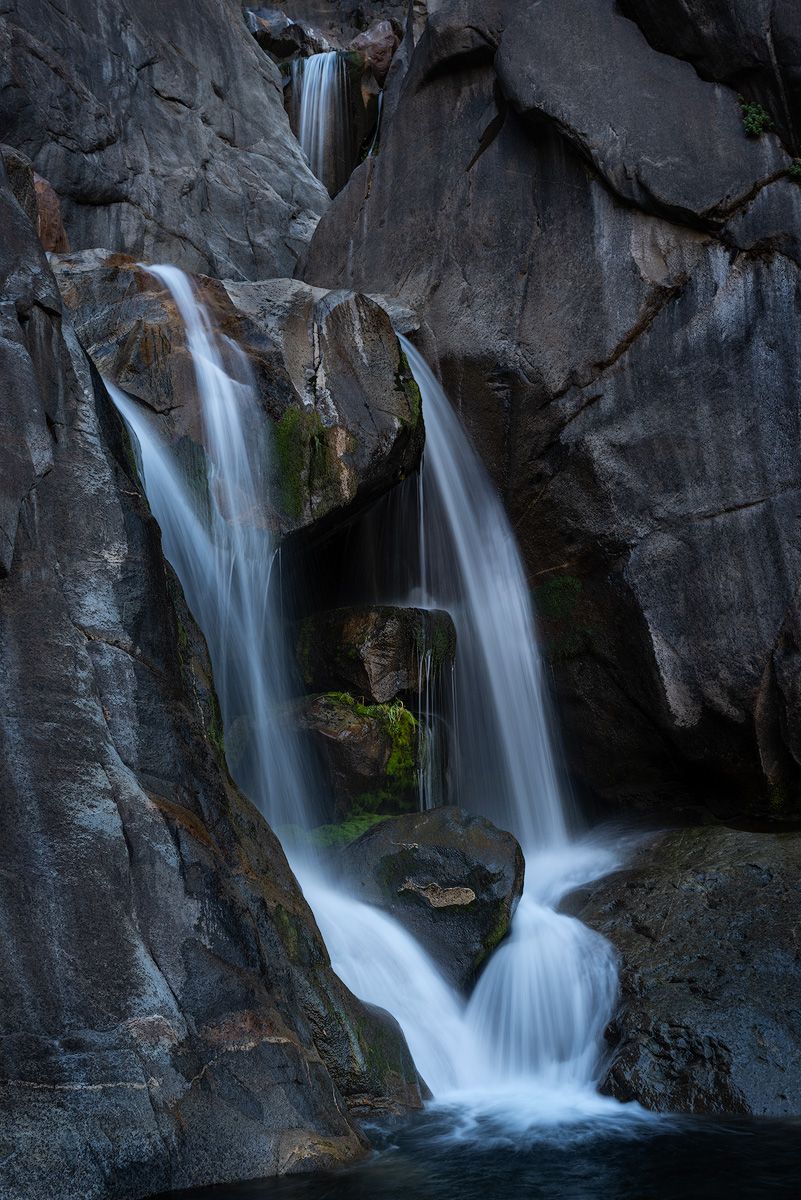 Multiple waterfalls cascade down dark granite cliffs in a dramatic natural display.