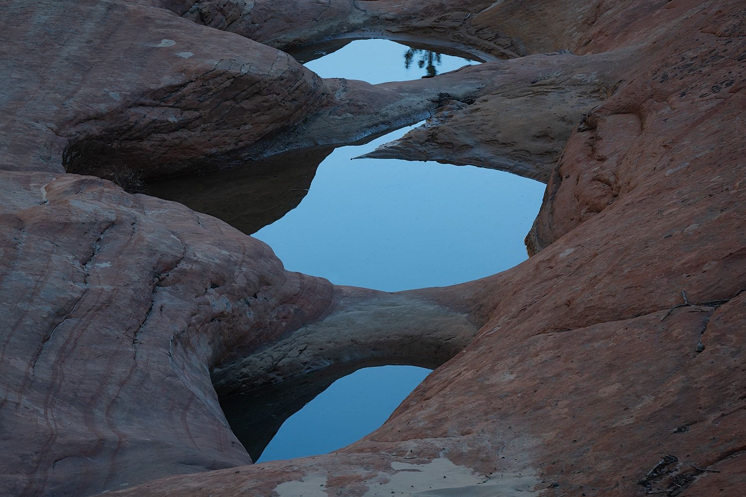 Stunning rock arch formation in Utah's desert landscape frames a bright blue sky through its natural window.