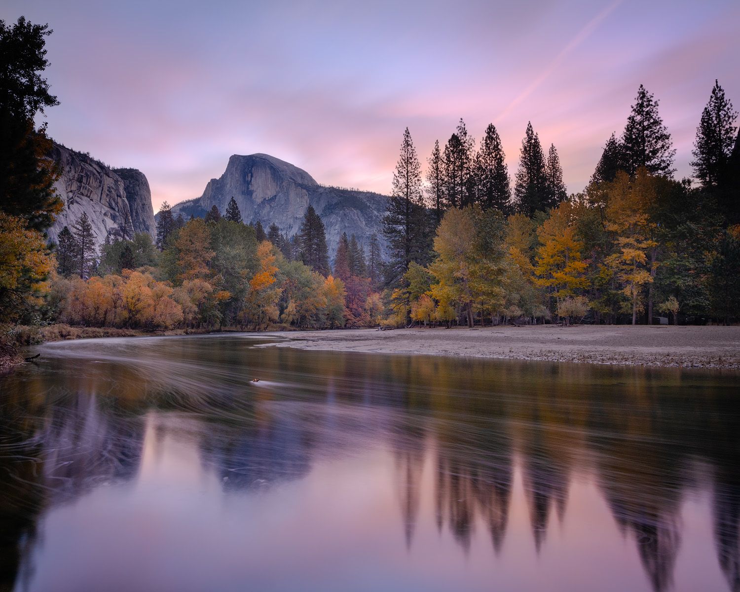 Half Dome reflecting in mirror-like river at sunrise in Yosemite National Park.