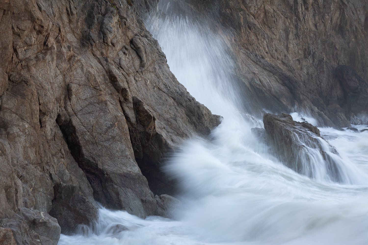 Powerful waves crashing against rocky coastal cliffs creating dramatic water spray.