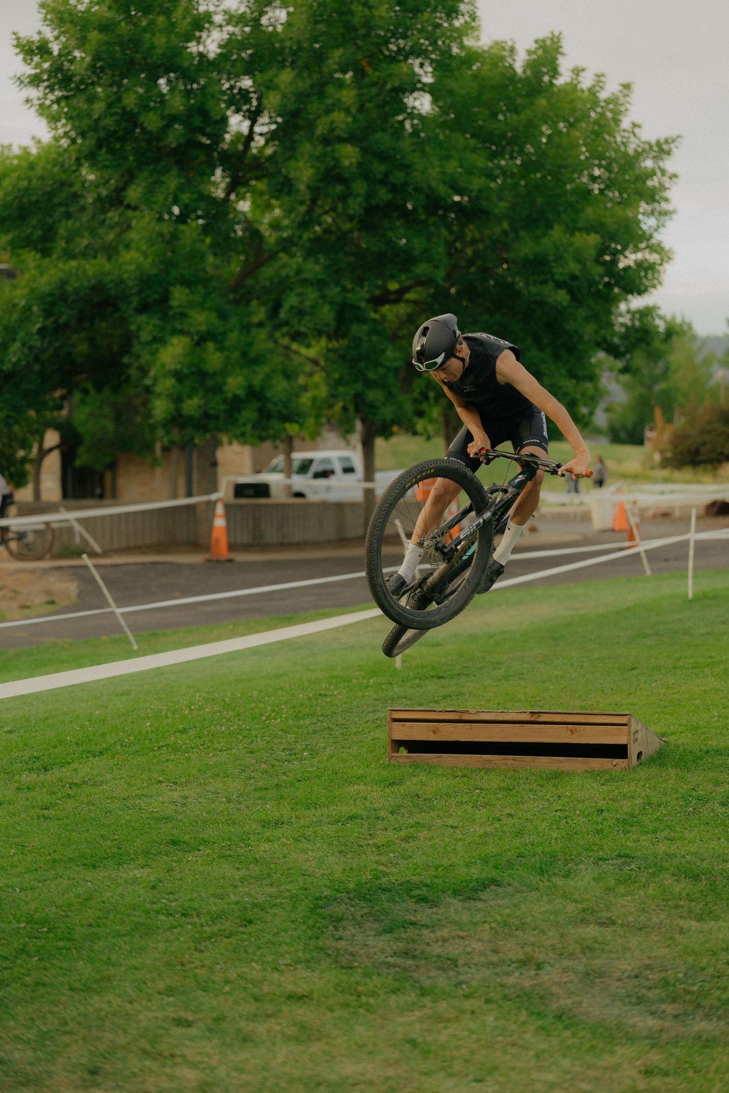 A sequence showing a BMX rider performing a high-flying jump trick off a wooden ramp on a grassy slope.