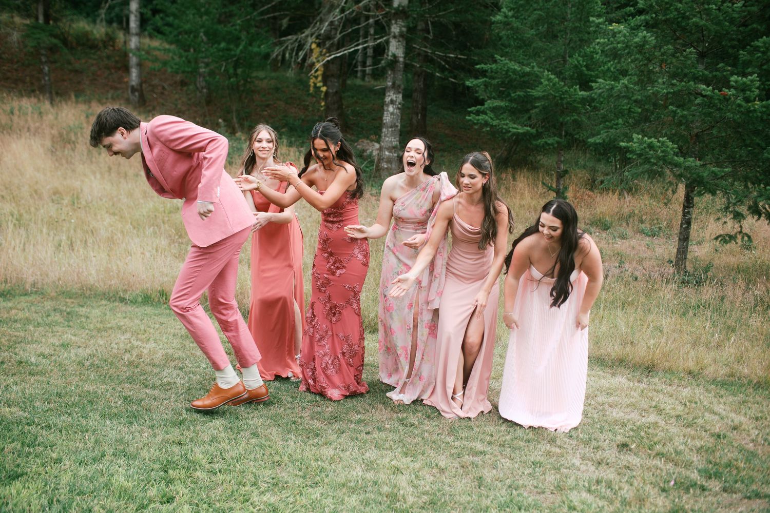 Candid wedding party in pink and coral dresses poses together outdoors - Adrianna Elizabeth Photography.