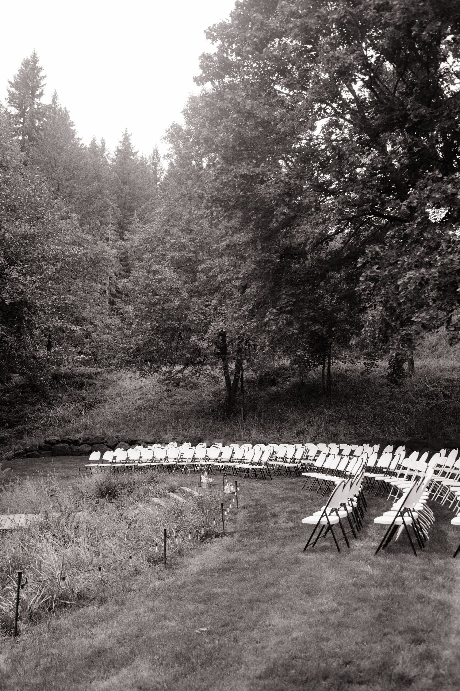 Curved rows of white chairs set up for an outdoor wedding ceremony in a natural meadow setting on 35mm film - Adrianna Elizabeth Photography