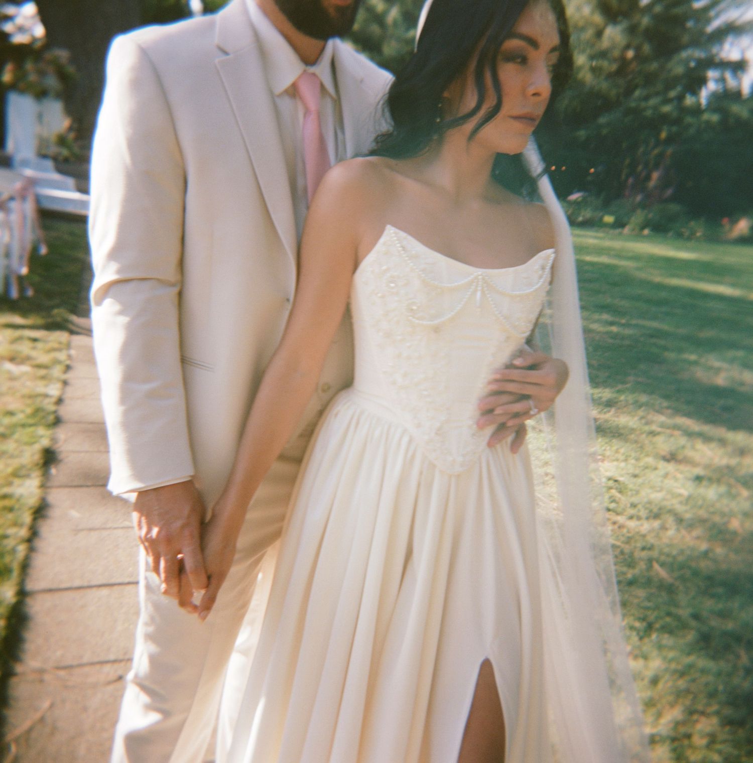 A close-up view of a wedding dress detail showing delicate lace and fabric textures in natural outdoor lighting.