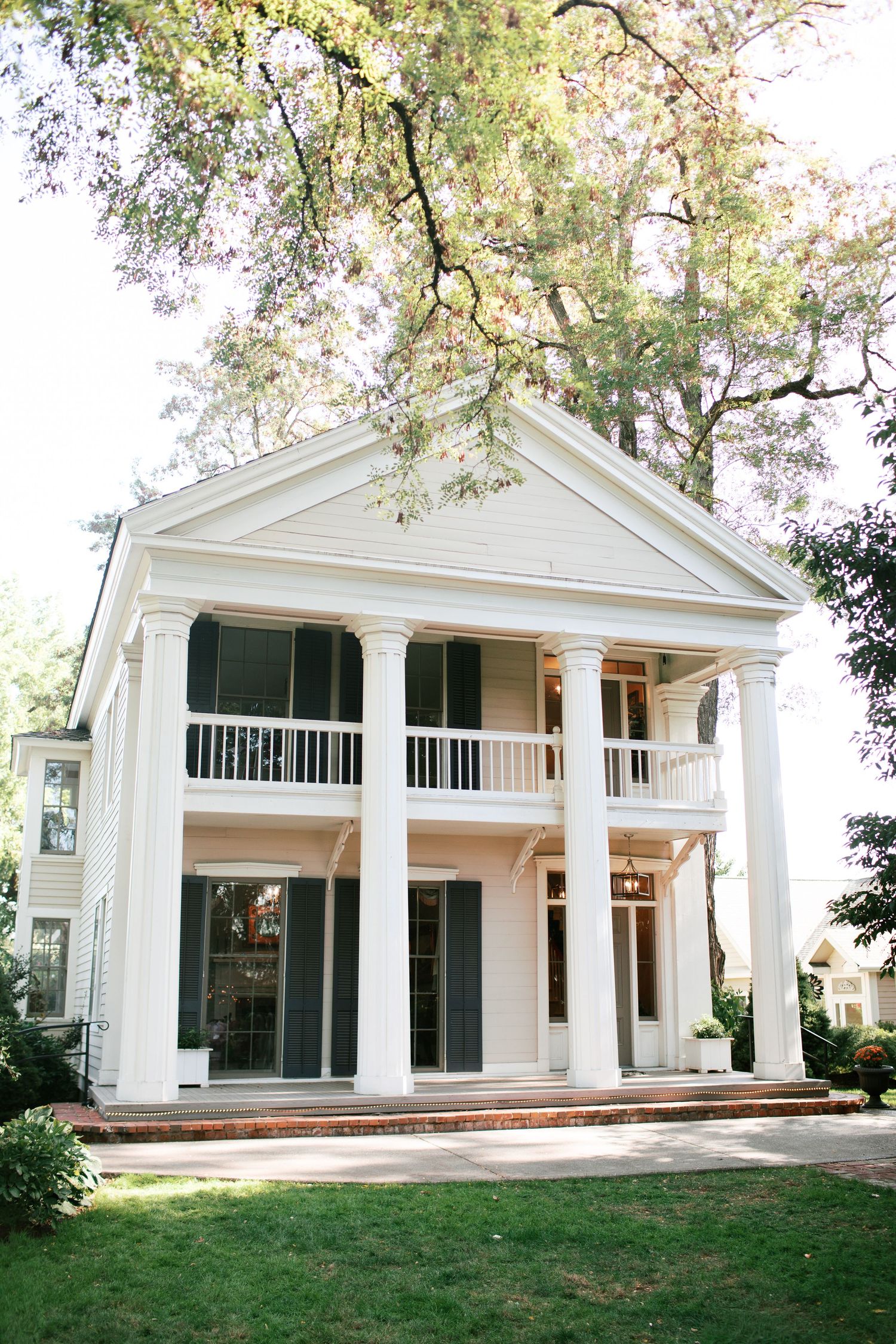 White colonial style house with large windows and pillars shown from different angles on a grassy lawn.