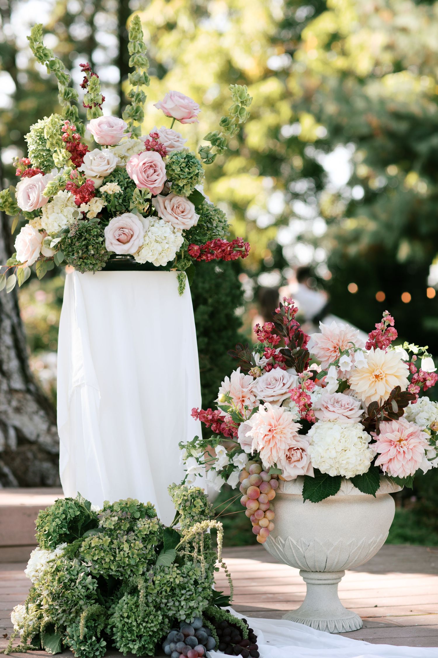 White vases filled with pink roses, dahlias, and greenery create an elegant garden-inspired floral arrangement display.