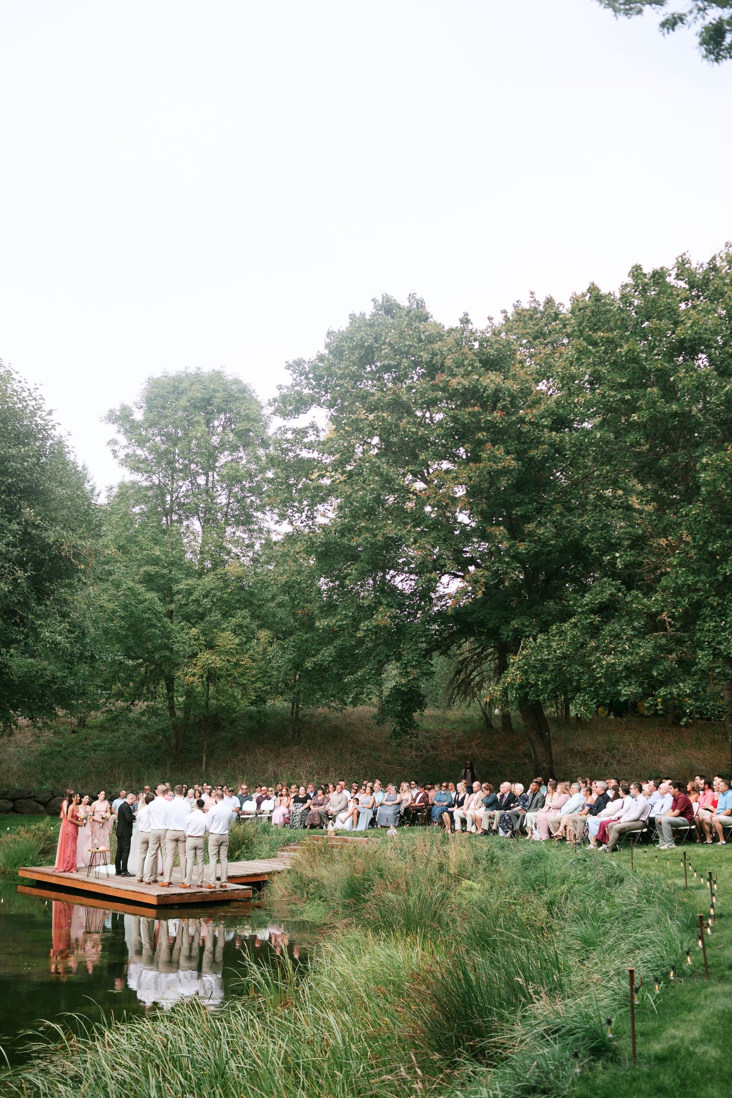 Outdoor wedding ceremony setup with rows of chairs and decorative elements in a lush green field - Adrianna Elizabeth Photography.