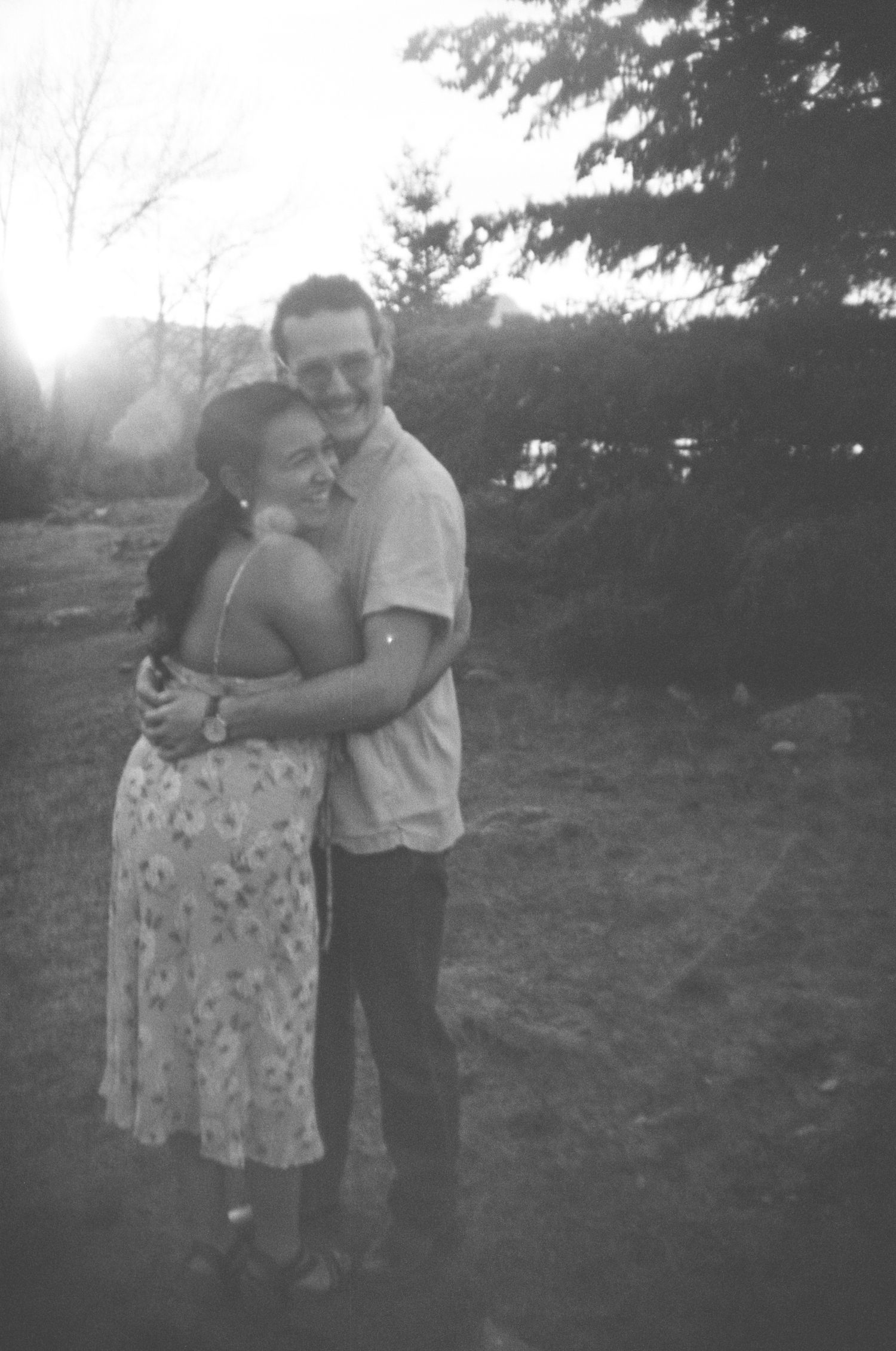 A couple embraces outdoors in a vintage black and white photograph from what appears to be the 1950s.