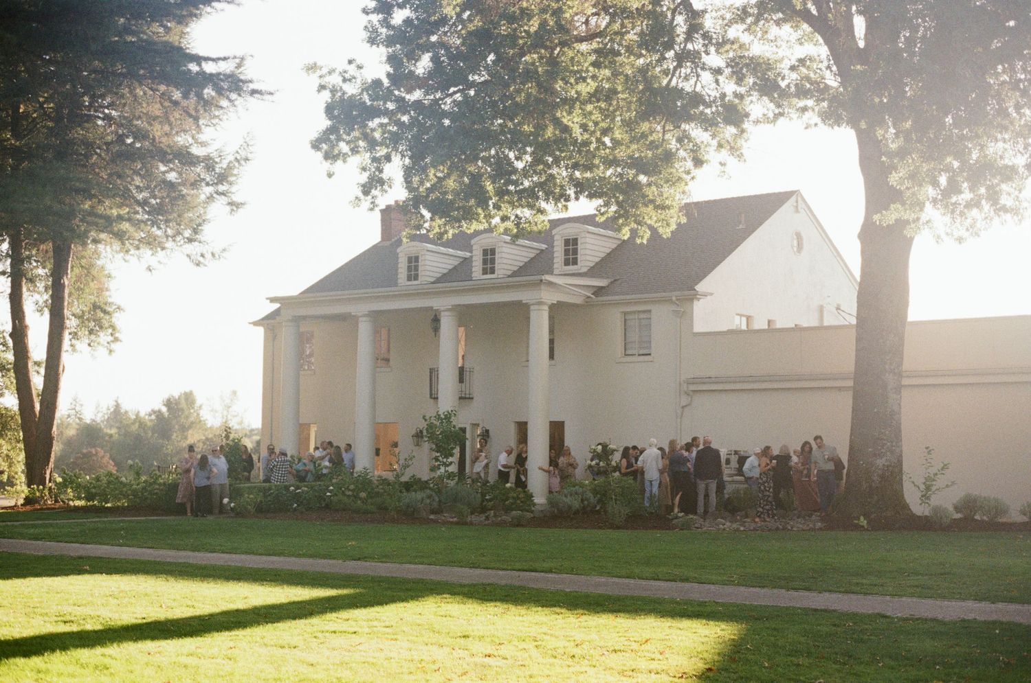 White colonial style house with columns and green lawn shown from multiple angles in bright sunlight.