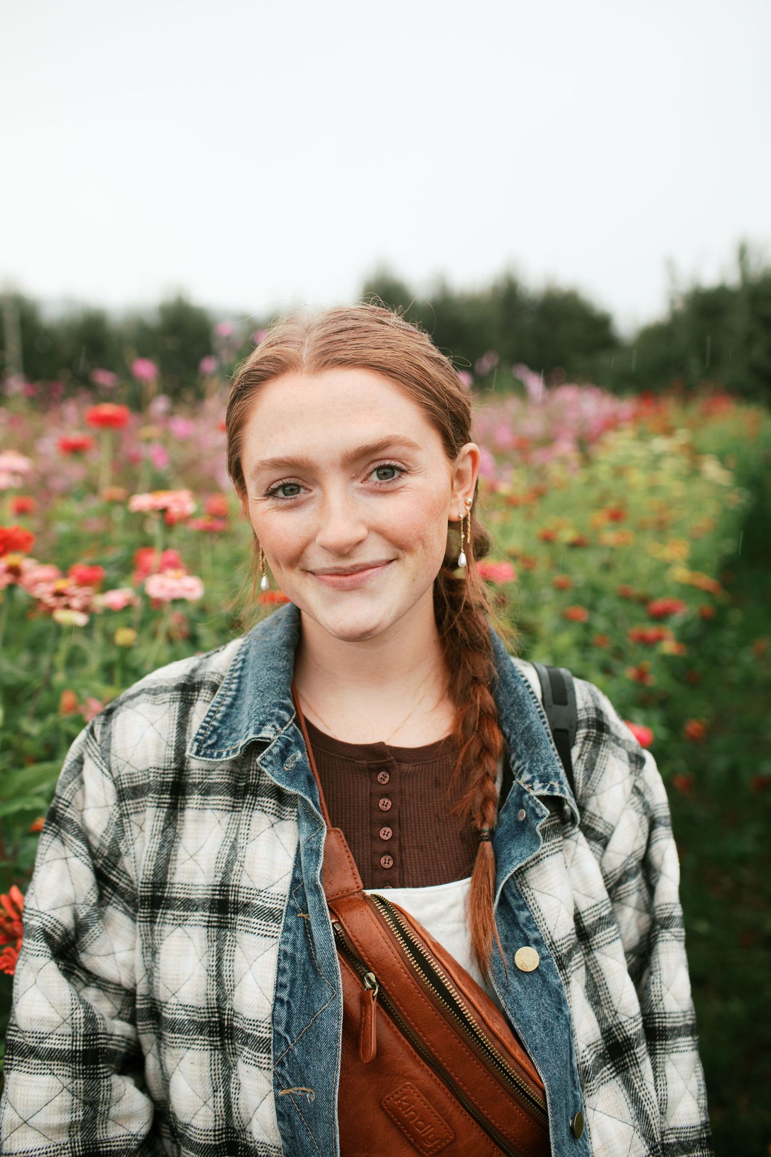 Adrianna Elizabeth photography smiles while standing in a field of red wildflowers on a sunny day.