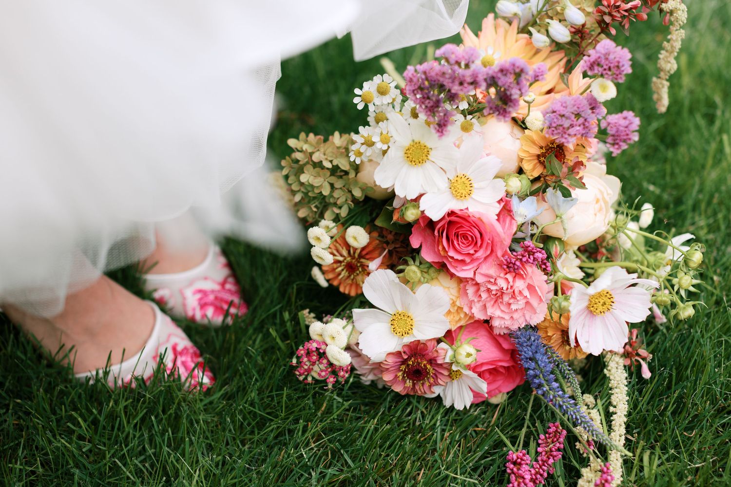 Romantic floral wedding bouquet featuring pink roses, daisies and purple accents on grass-Adrianna Elizabeth Photography.