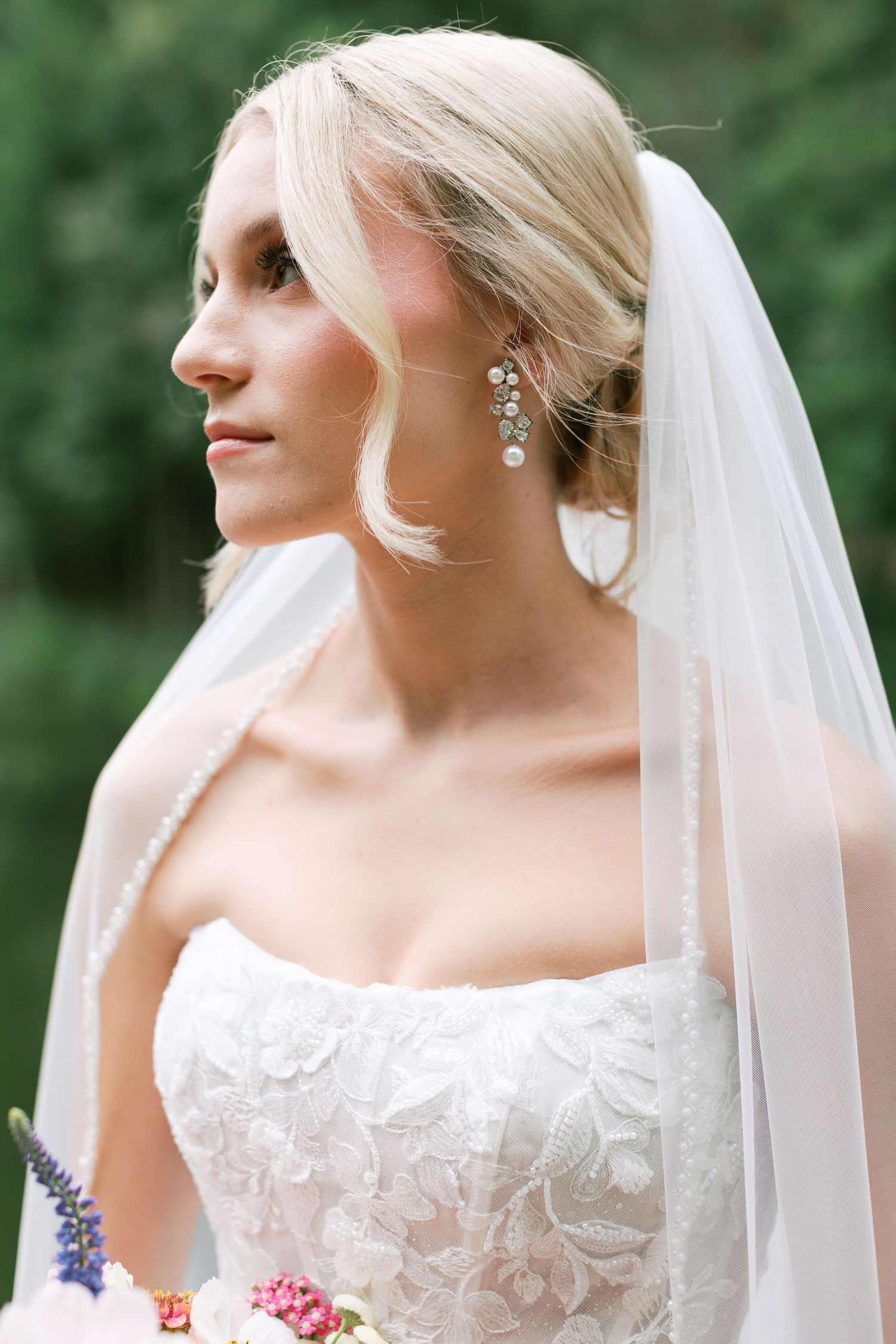 Close up details of a bride wearing pearl earrings and delicate veil against green foliage-Adrianna Elizabeth Photography.