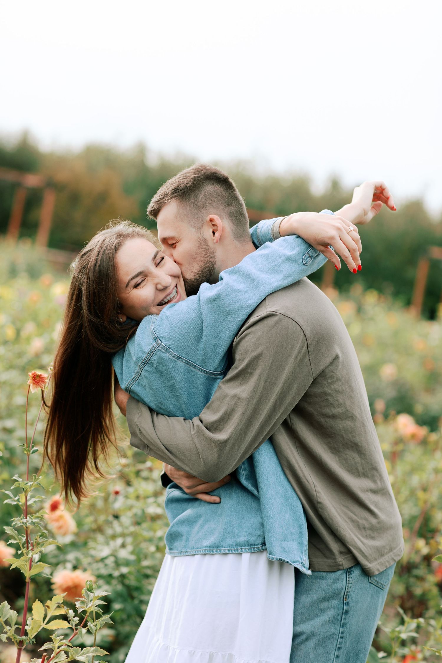 A couple embraces romantically in a blooming wildflower field on a sunny afternoon.