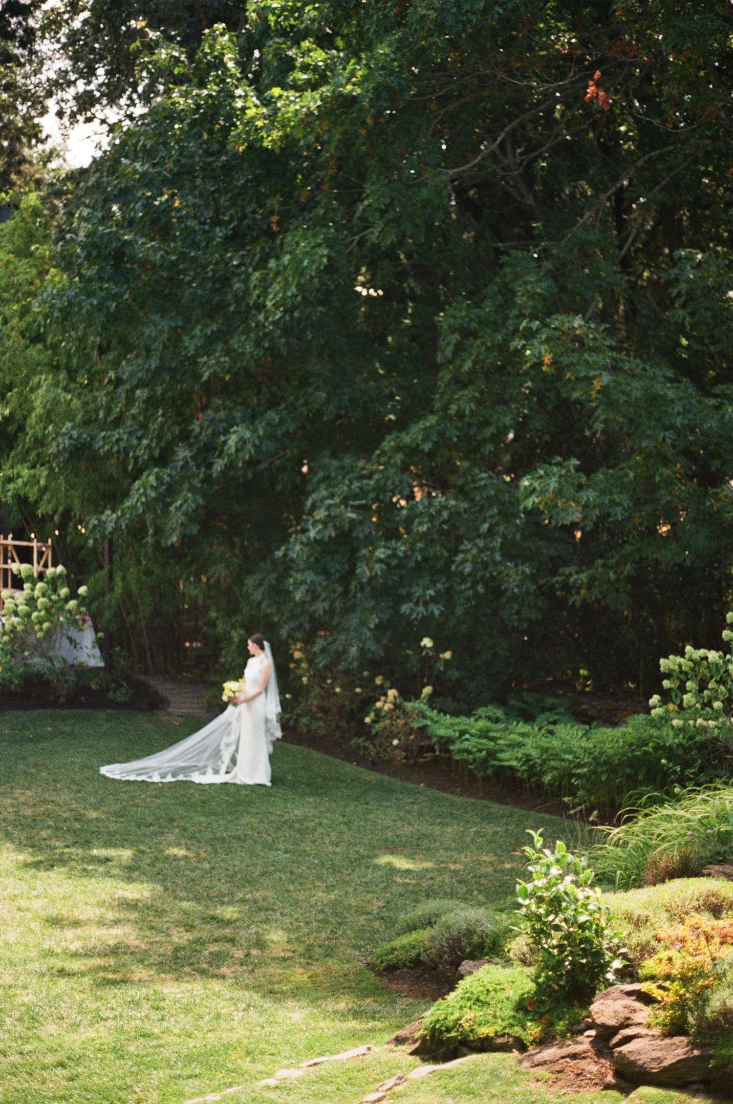 A beautiful outdoor wedding photo session in a lush garden setting with natural greenery and sunlit grass.