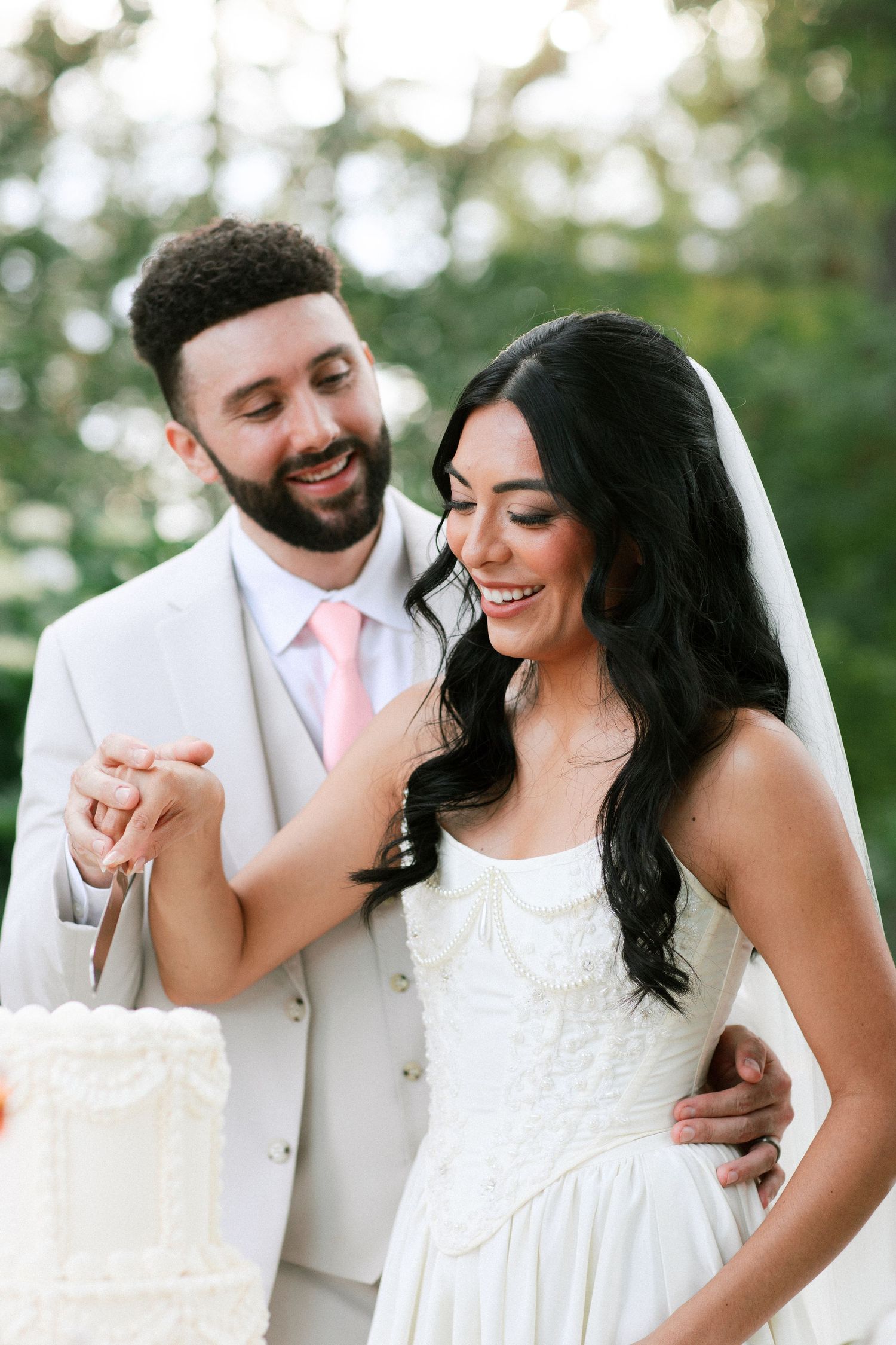 A joyful couple shares sweet moments together while wearing wedding attire in an outdoor setting.