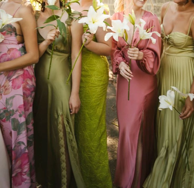 Bridesmaids in elegant floral and solid dresses in pink and green tones hold white lily bouquets at outdoor wedding.
