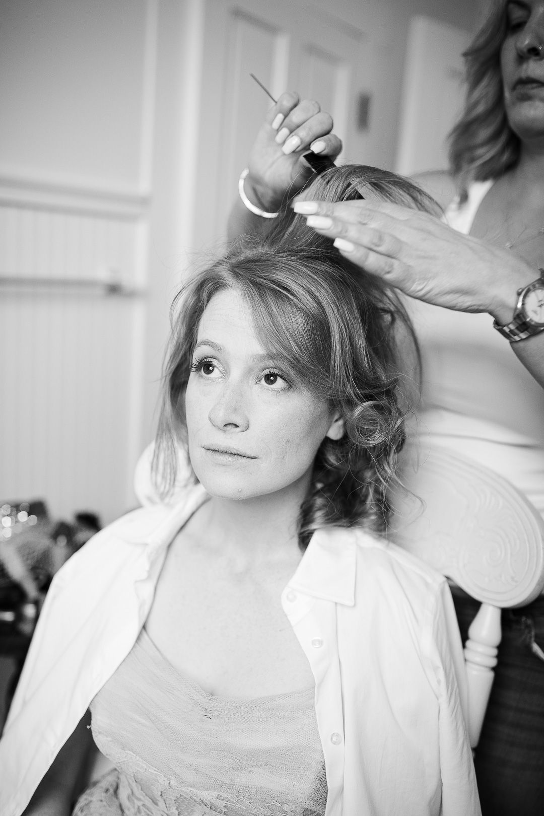 A series of black and white photos showing someone getting their hair styled in a bright indoor setting.