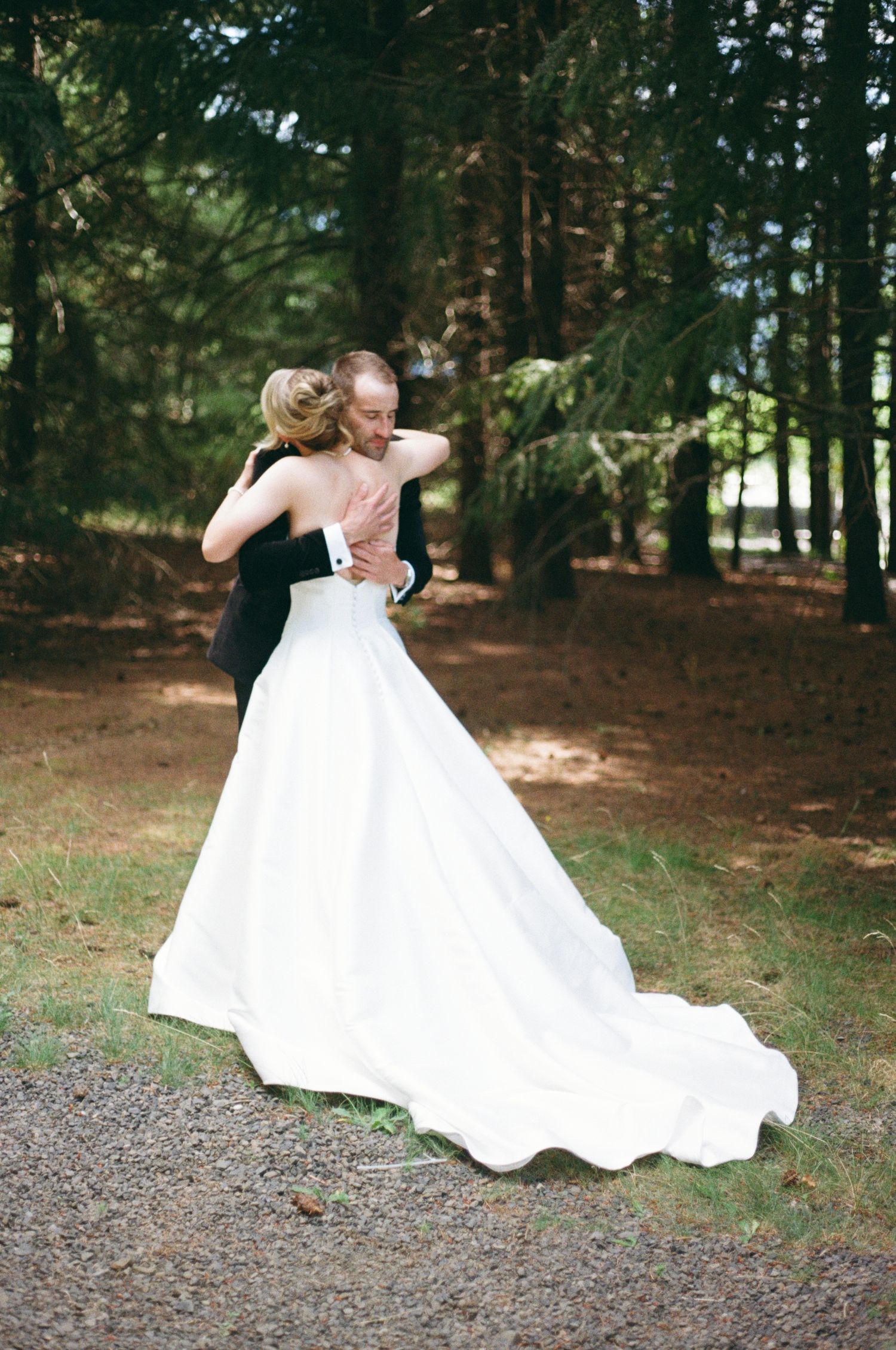 First look in a romantic forest setting, with the bride wearing a flowing white gown with a long train-Adrianna Elizabeth Photography.