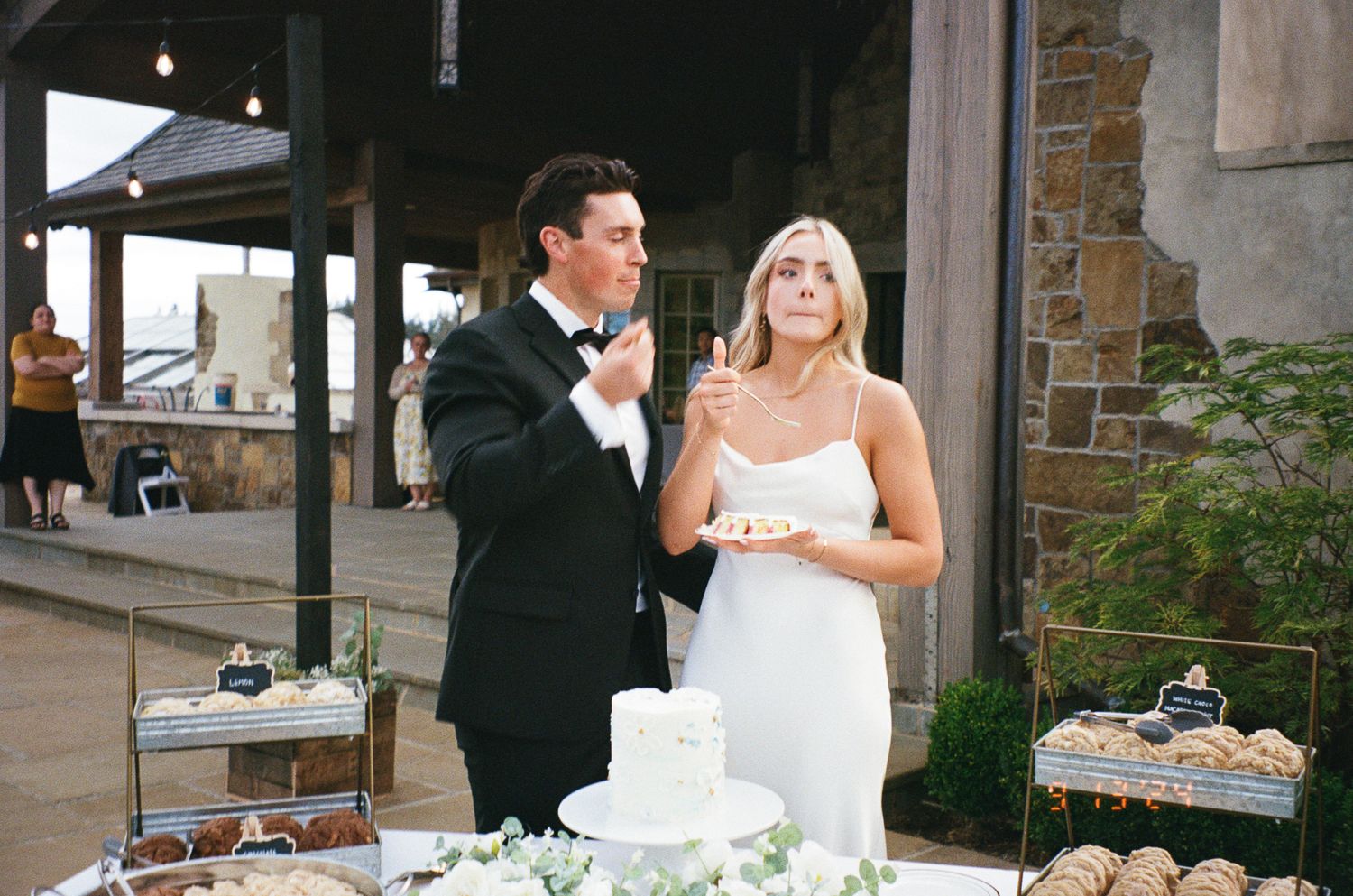 A wedding couple cuts their rustic white wedding cake at an elegant reception venue.