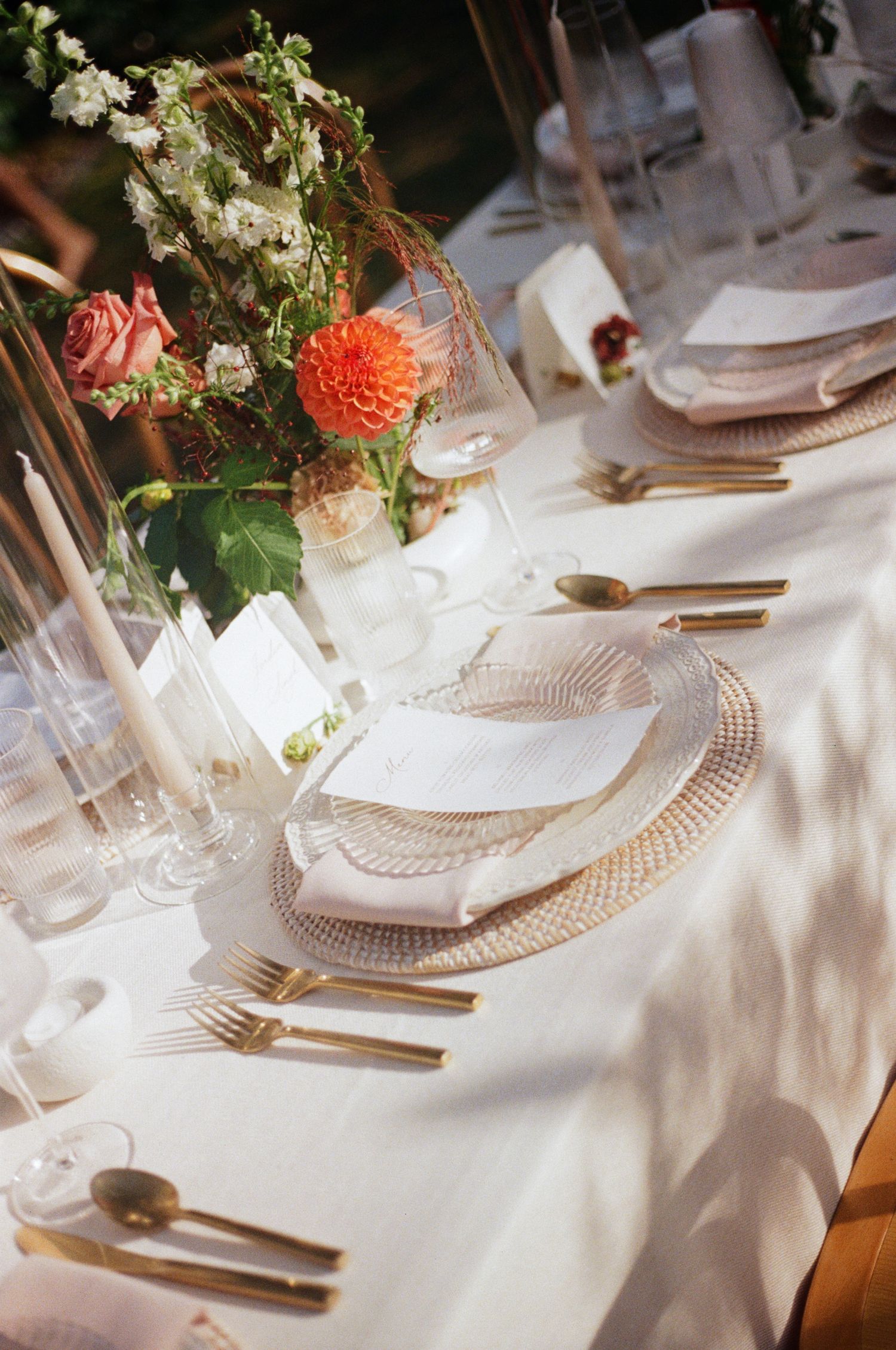 Elegant white table settings with crystal glassware and gold cutlery at a formal dining event.