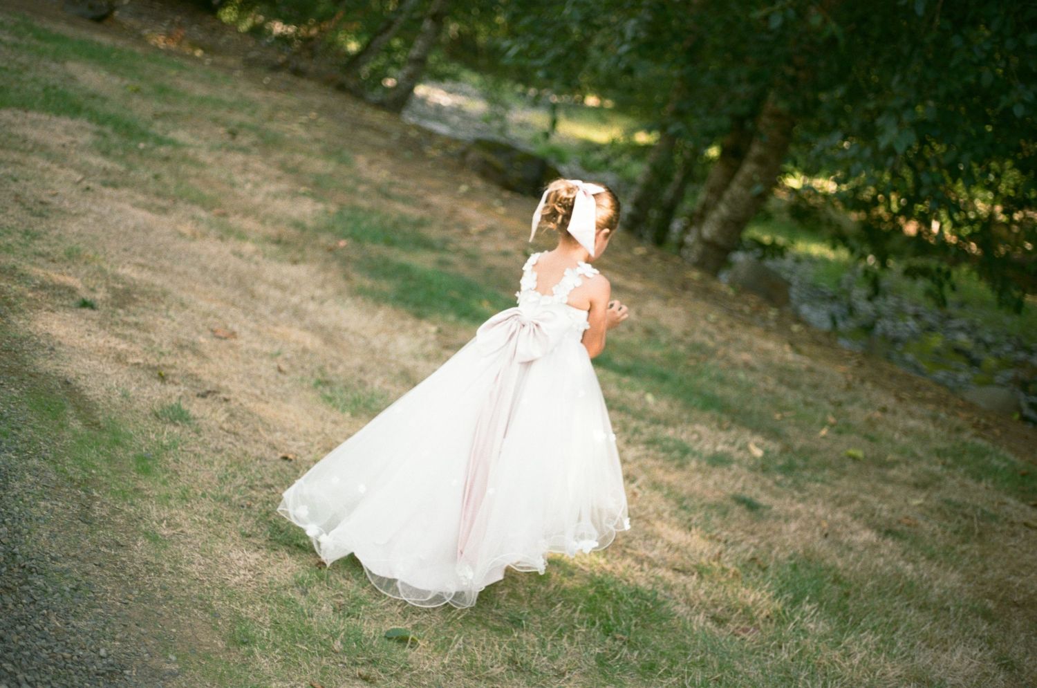 A flowing white wedding dress twirls gracefully in motion across a grassy outdoor setting.
