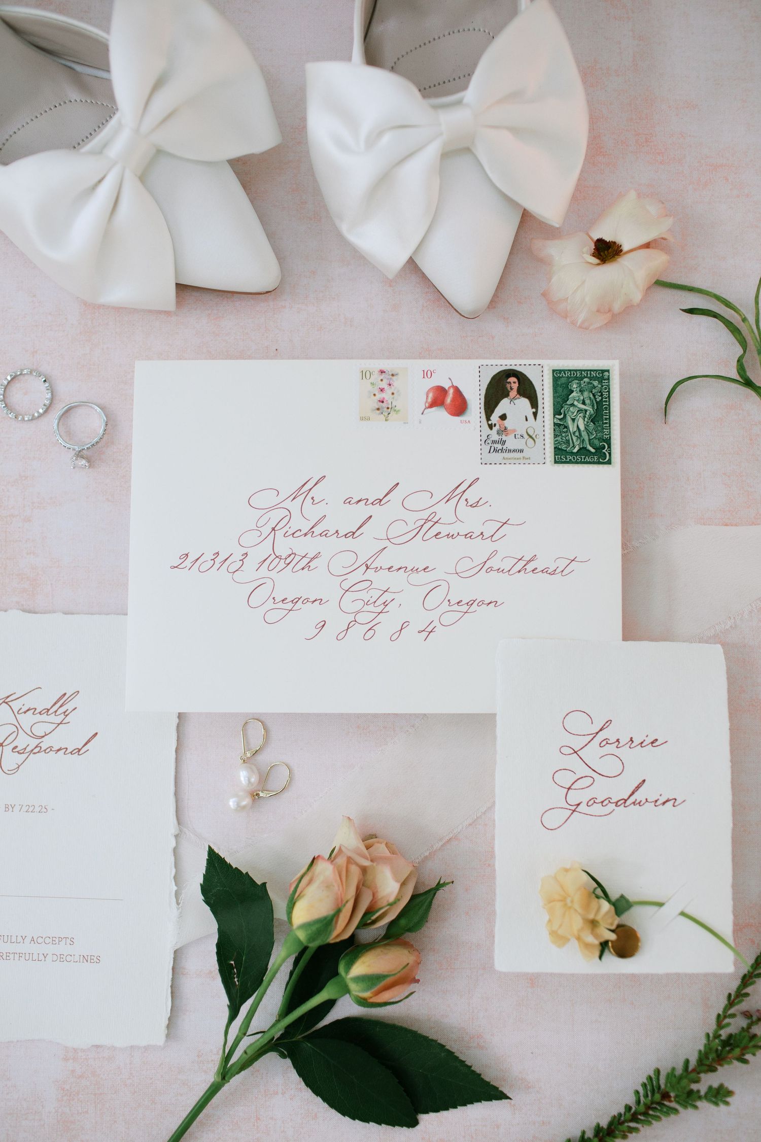 Wedding invitation suite with elegant calligraphy, white bows, and delicate peach roses on a light pink background.