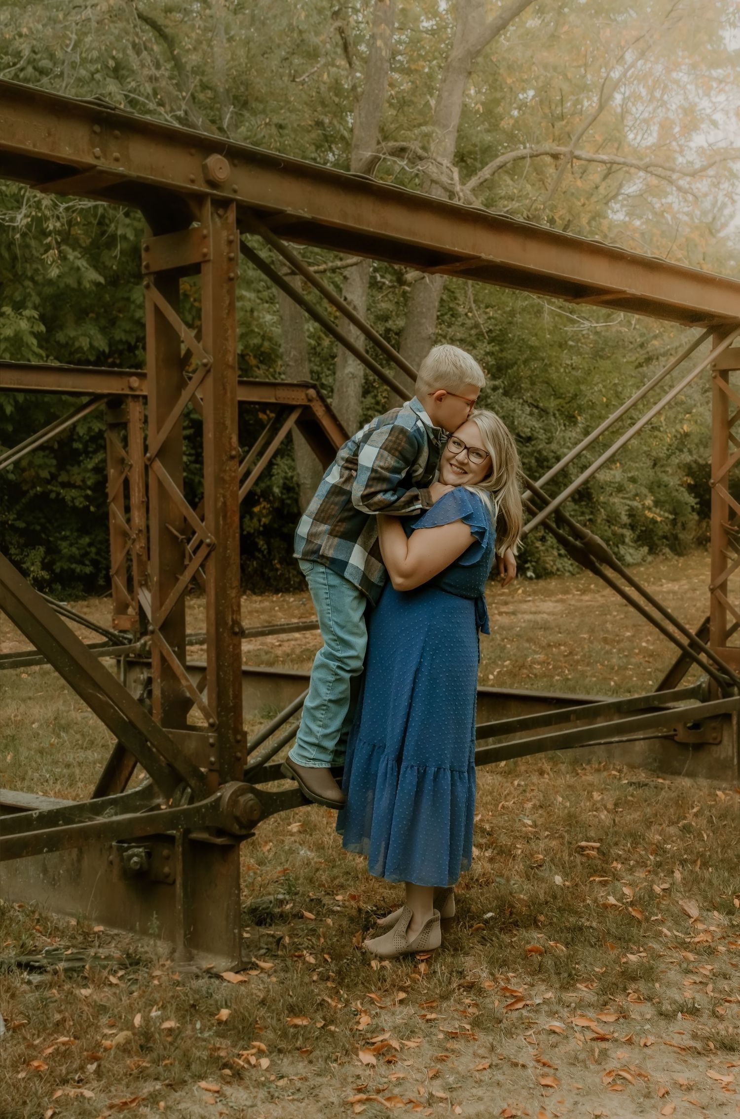 Son leaning into mom and kissing her on the forehead during a tender moment at comlara park captured by bloomington il family photographer