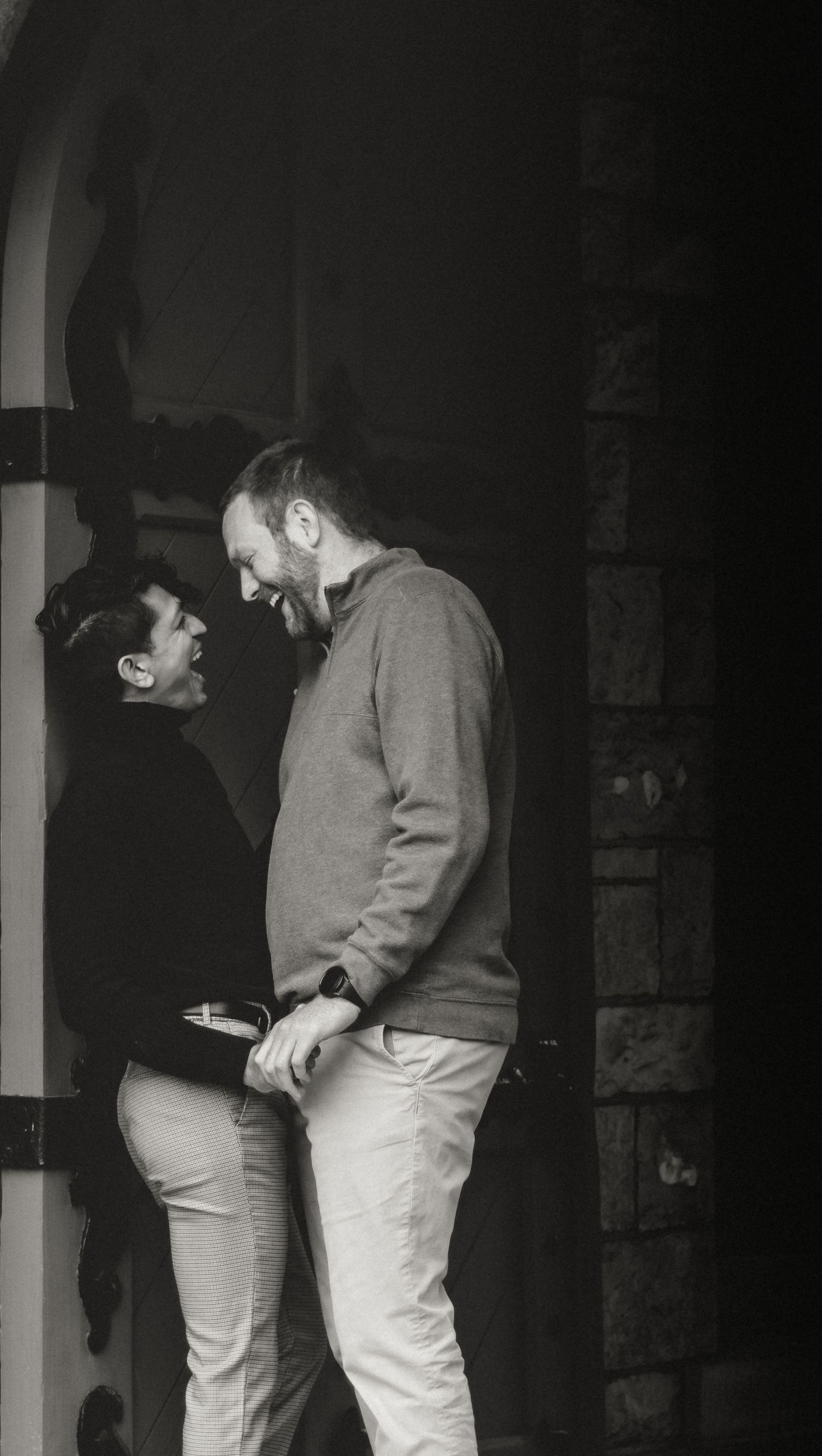 lgbtq+ couple leaning against a doorframe during an intimate playful moment captured by central il photographer