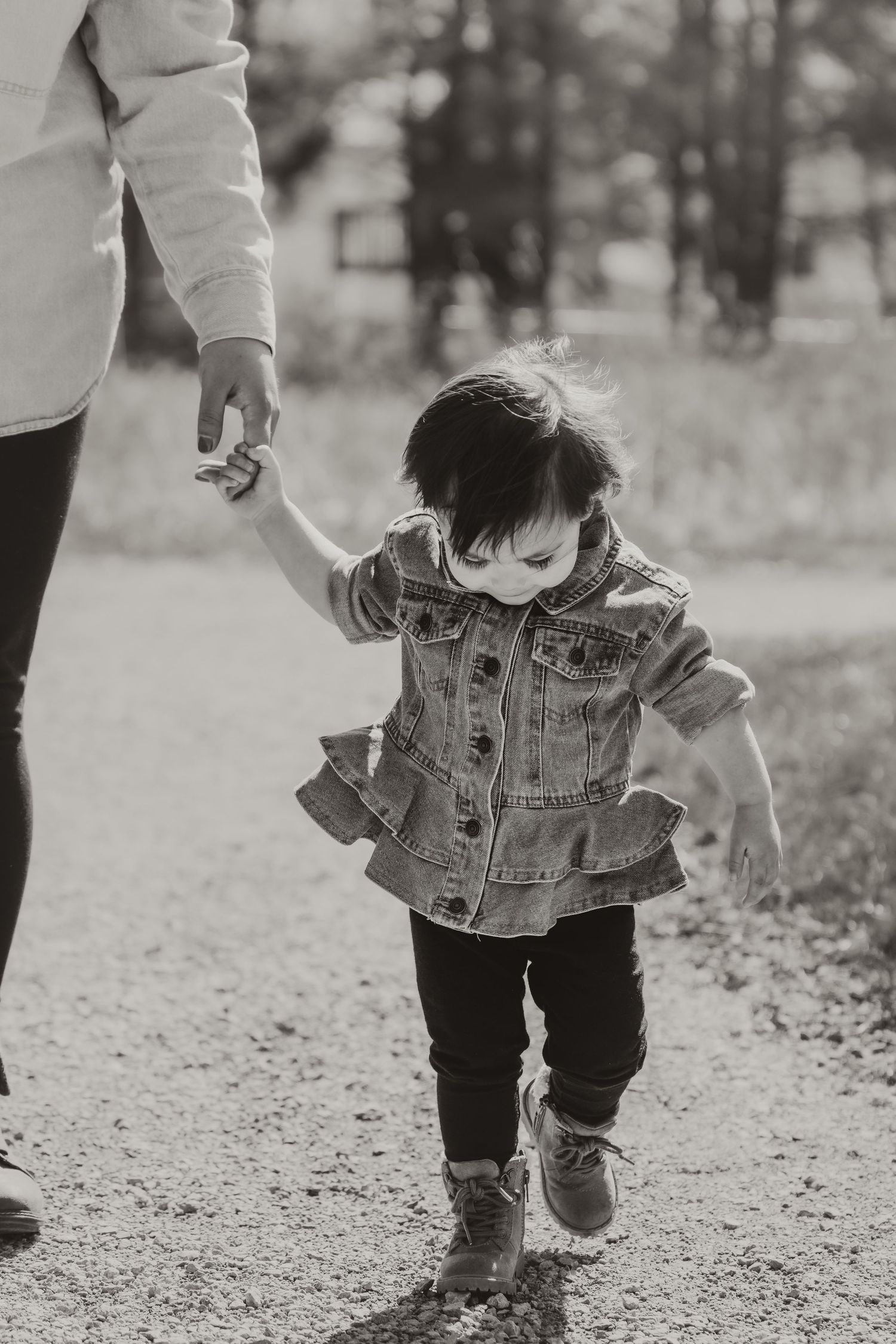 Little girl walking and holding her mom's hand during a family outing photo session